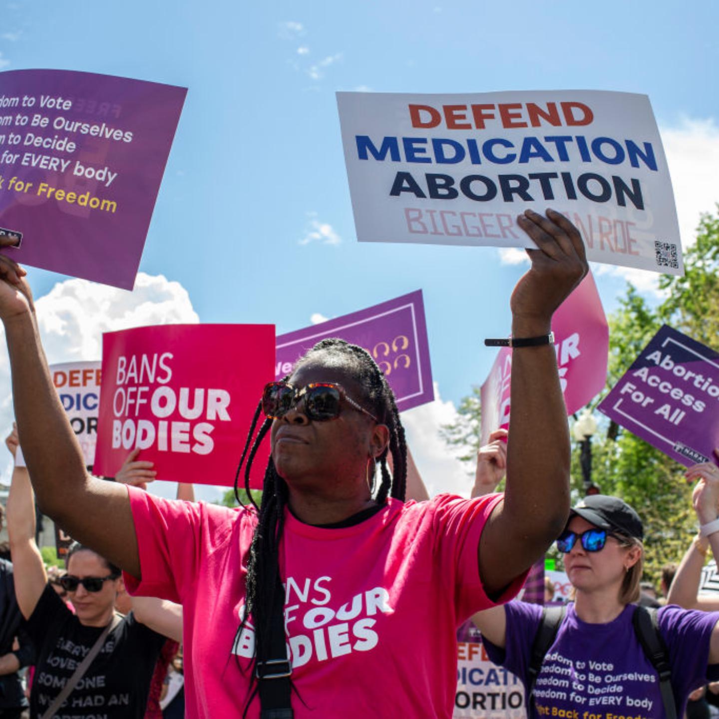 Activists holding abortion rights signs shout slogans during