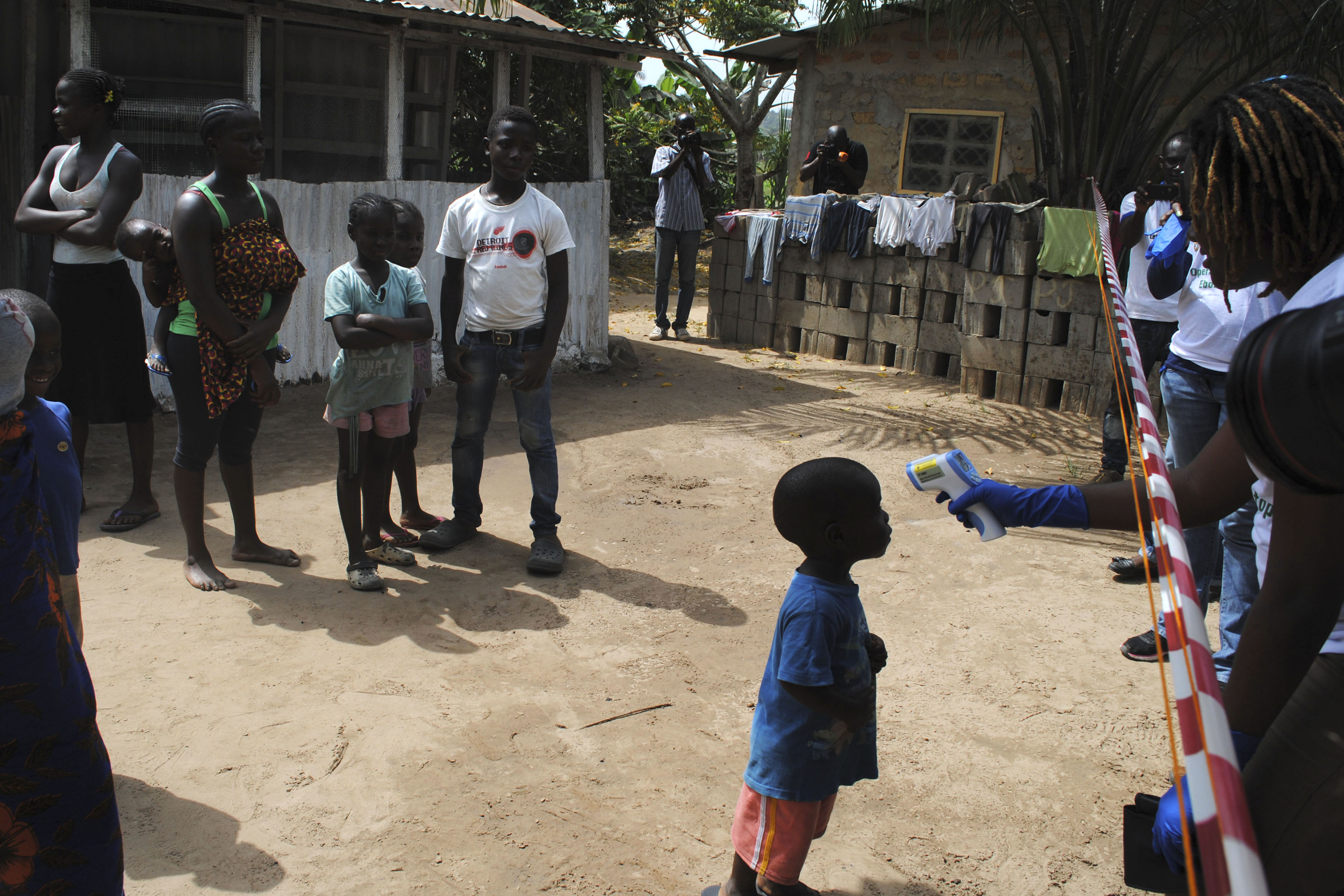 Health workers take temperature of boy who came in contact with woman who died of Ebola virus in Paynesville neighborhood of Monrovia