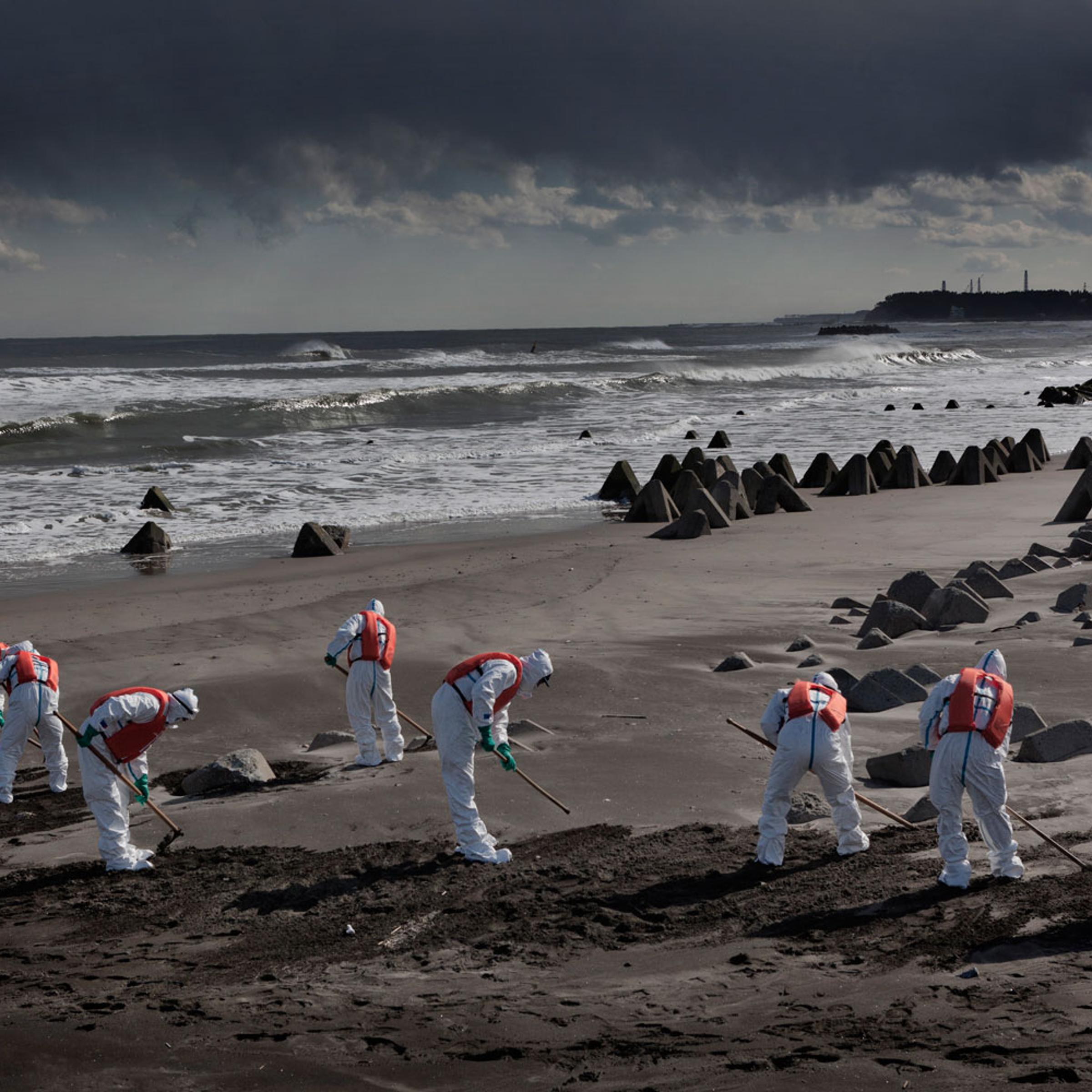 Feb. 27, 2012. Namie, Japan. Police from Futaba District Police Station, which is inside the exclusion zone, search for the dead and still-missing along the ocean front near the power plant, the stacks of which can be seen in the far distance.