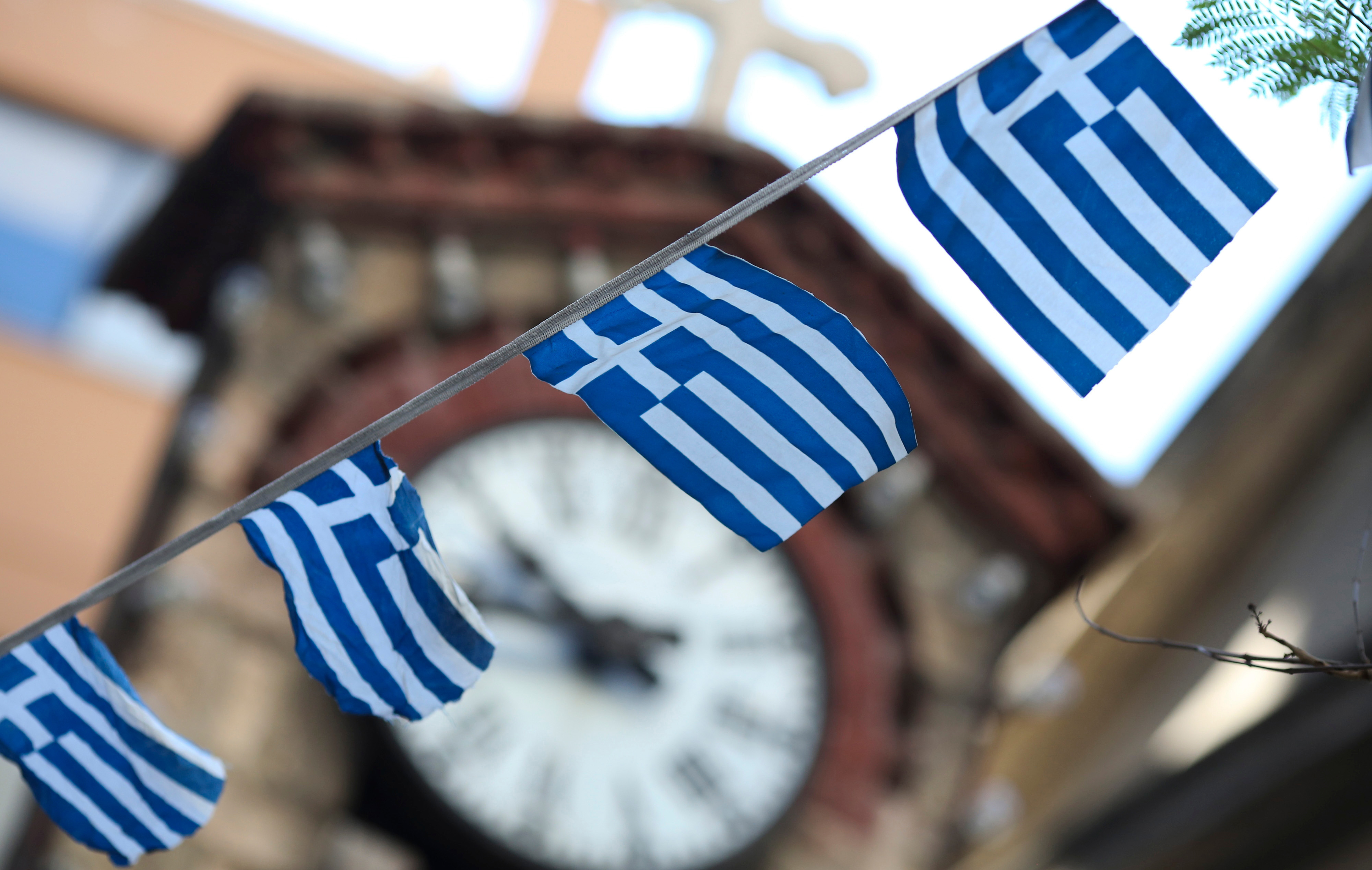Greek national flag bunting hangs in front of a church clock tower in the Plaka district of Athens, Greece, on Thursday, July 2, 2015.