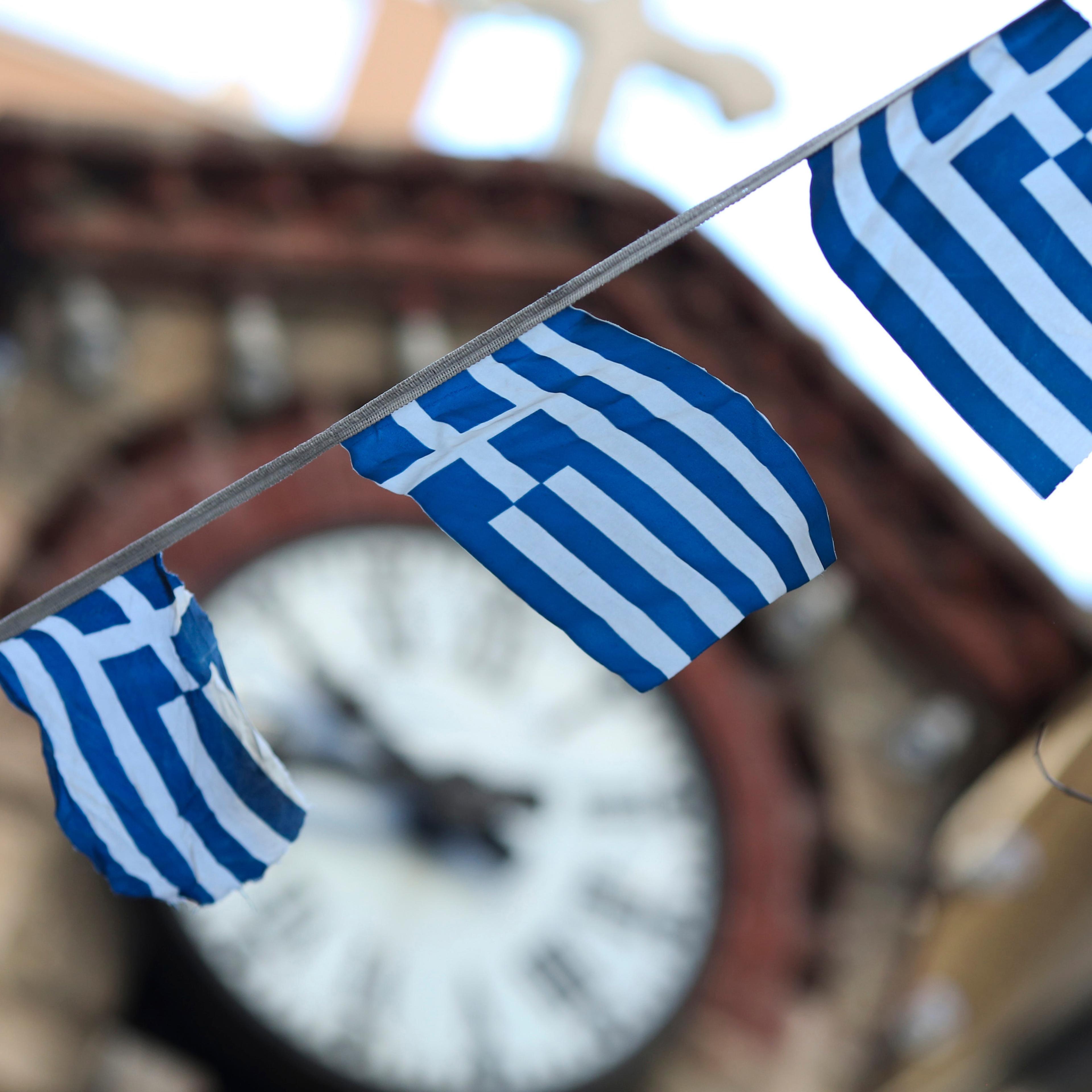 Greek national flag bunting hangs in front of a church clock tower in the Plaka district of Athens, Greece, on Thursday, July 2, 2015.