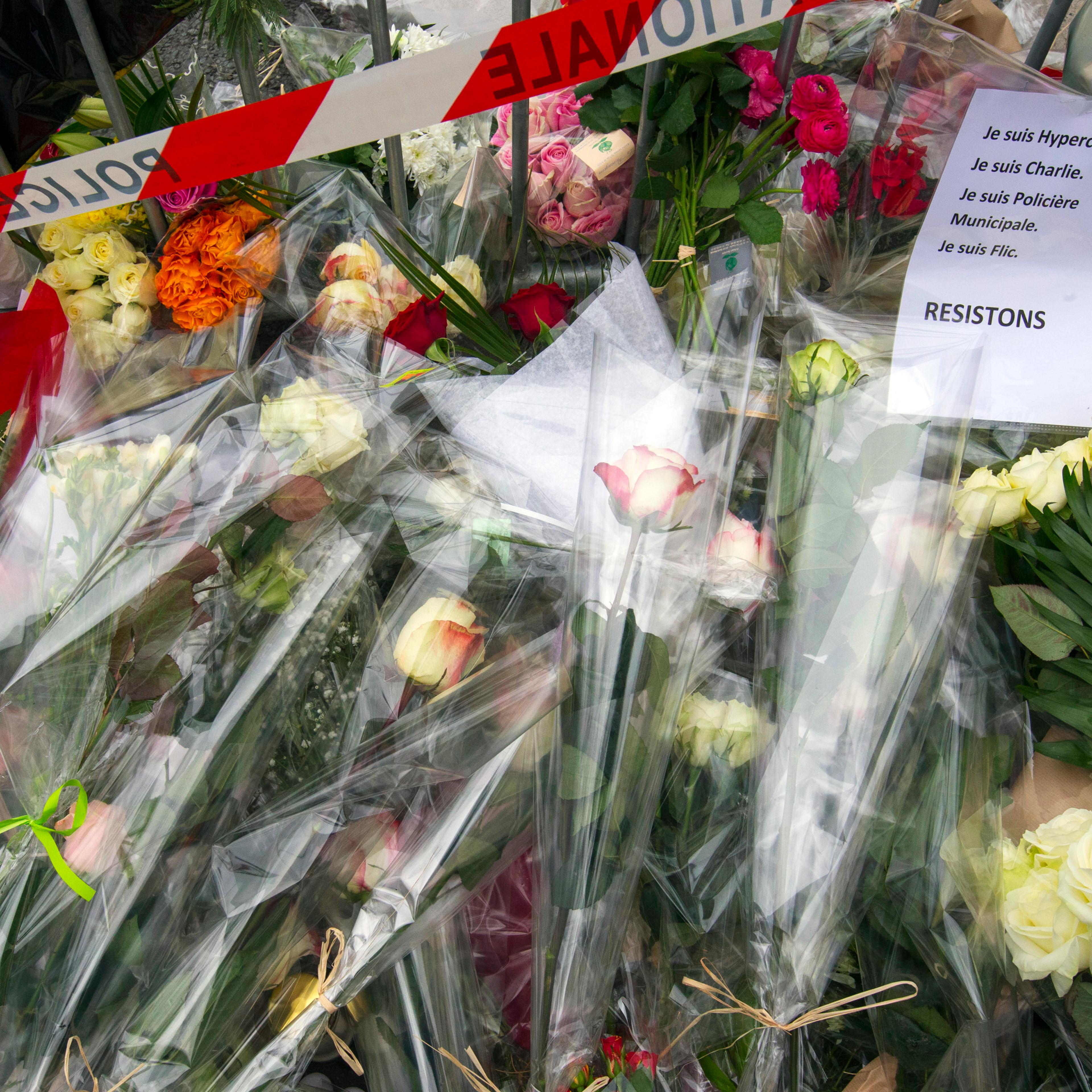A sign reading "I am Hypercacher, I am Charlie and I am police officer, we must resist" is placed among flowers outside the Hyper Cacher kosher supermarket near Porte de Vincennes in eastern Paris