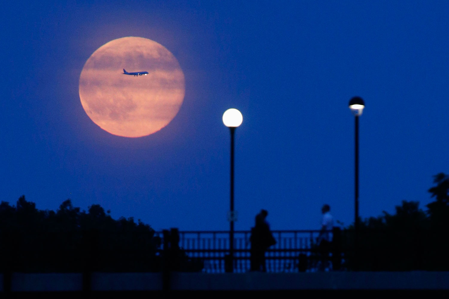 Aircraft passes in front of a Supermoon rising over the Rideau Canal in Ottawa