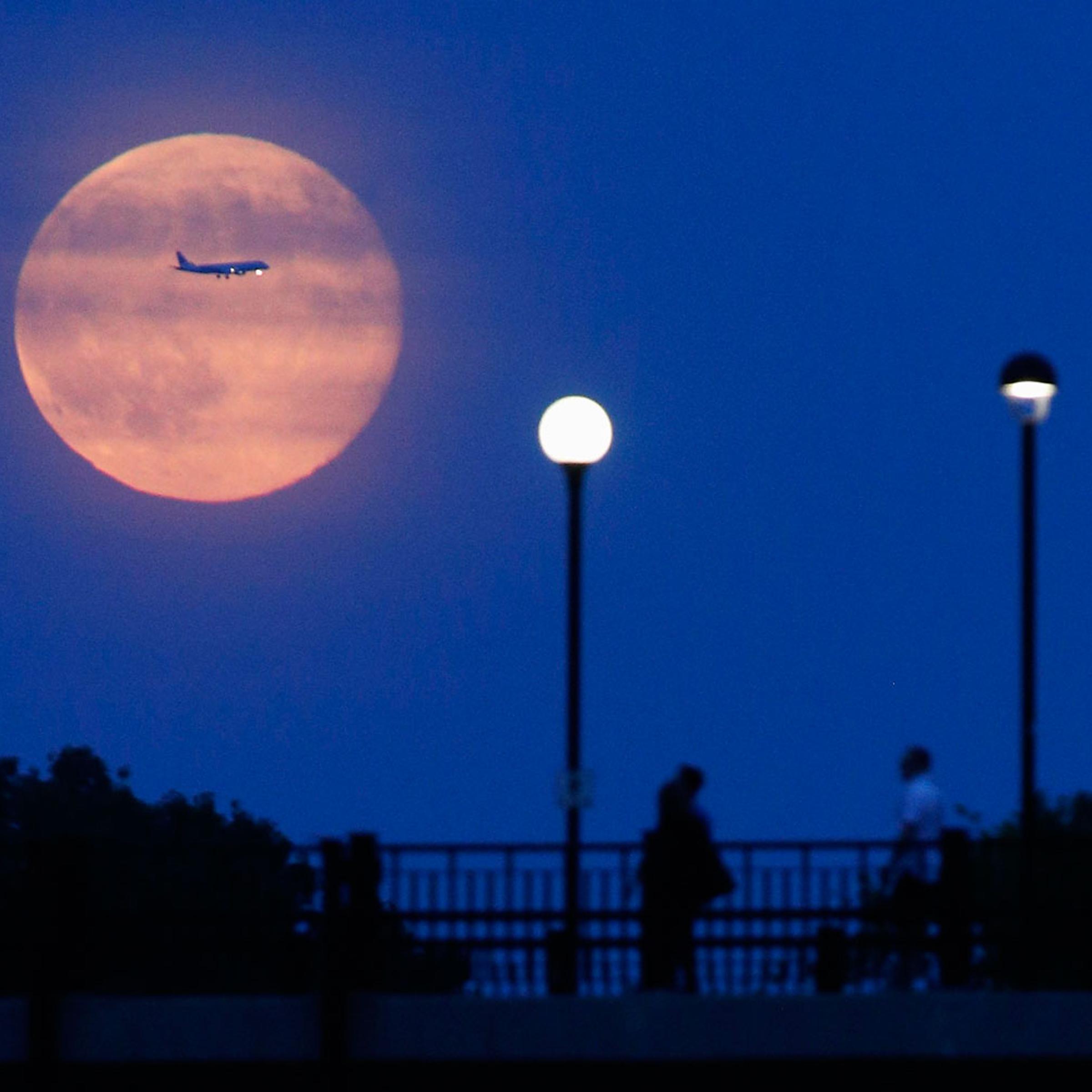 Aircraft passes in front of a Supermoon rising over the Rideau Canal in Ottawa