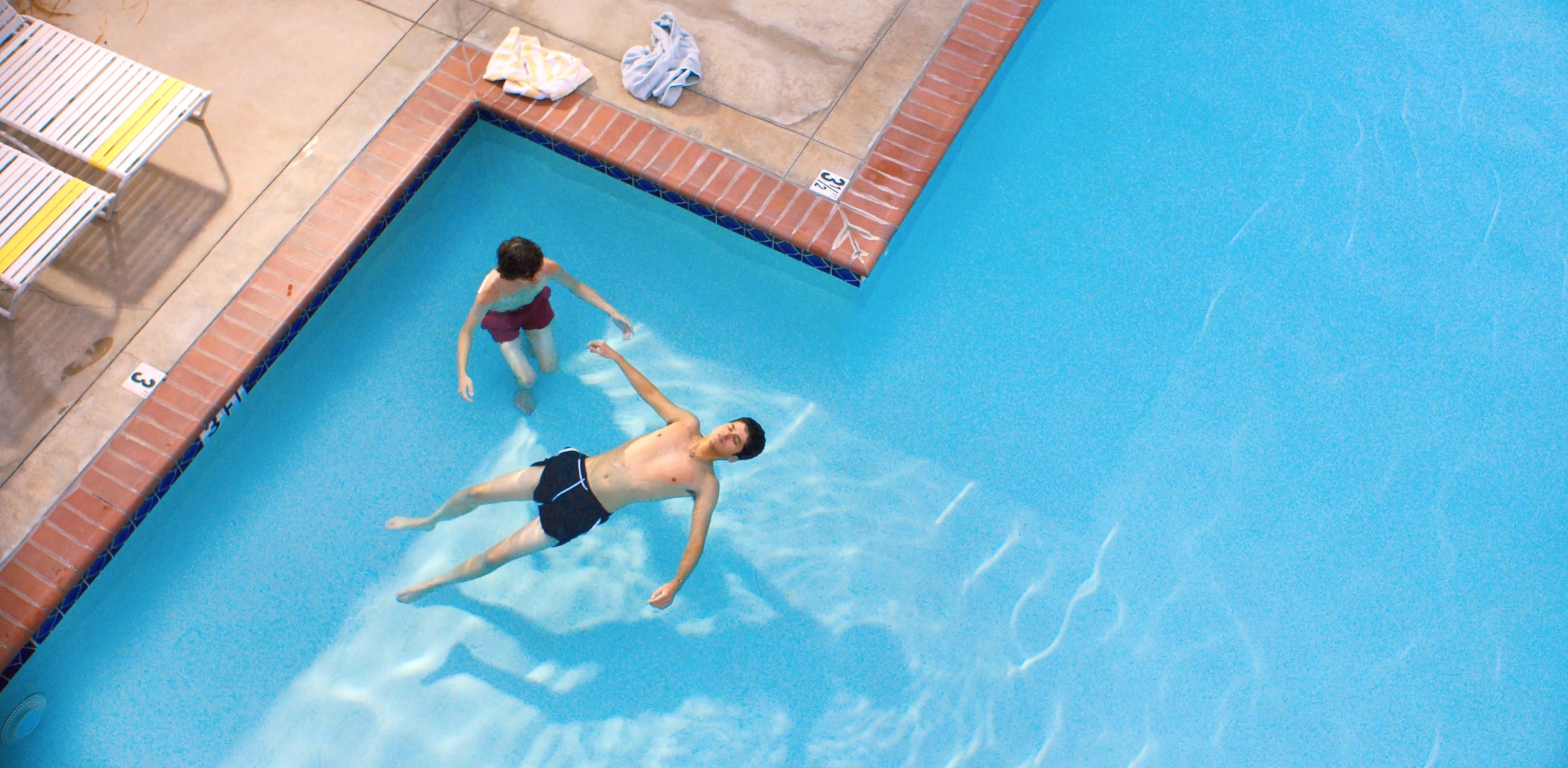 Dante (Reese Gonzales) teaches Ari (Max Pelayo) how to swim in a local pool.