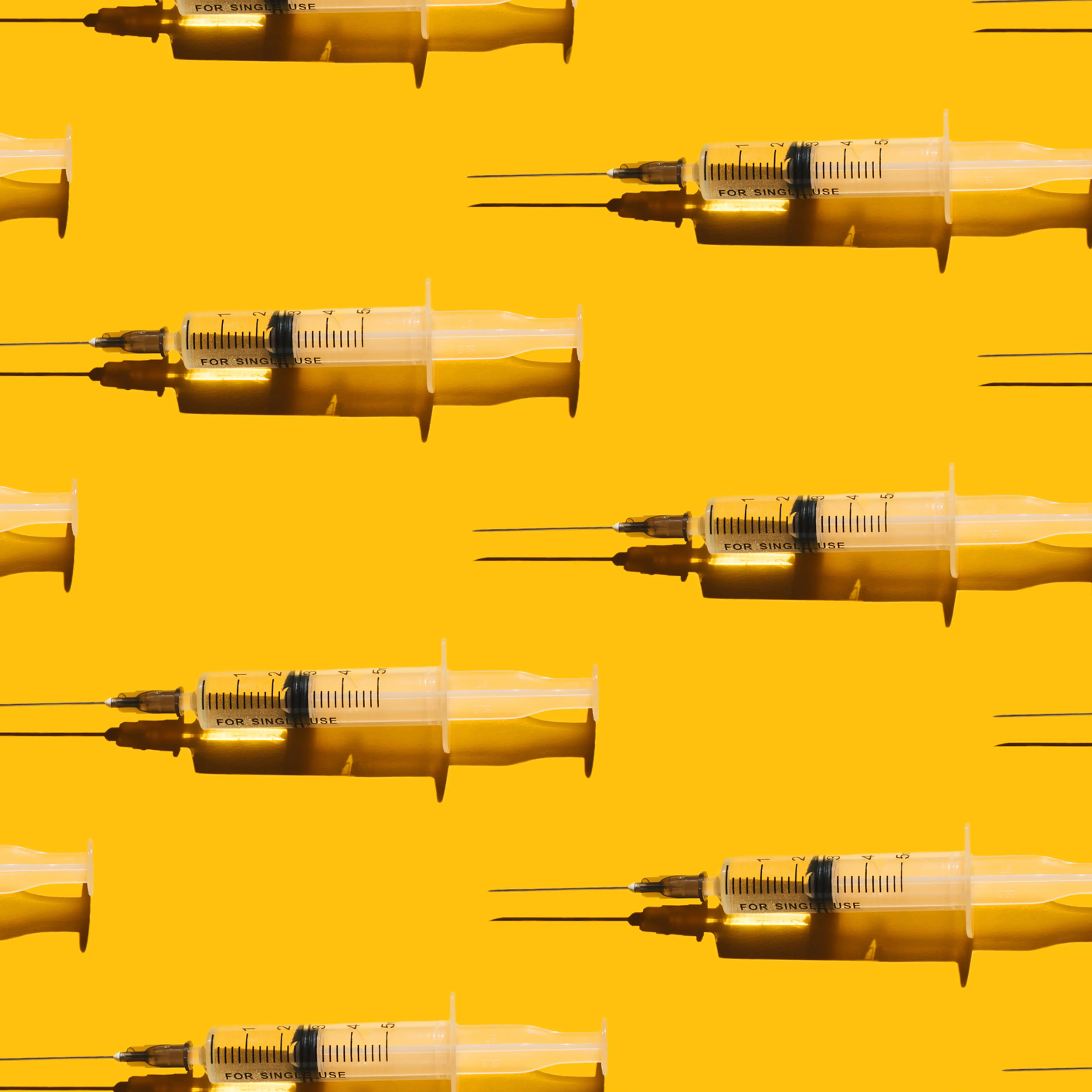 Pattern of syringes with a vaccine on yellow background. Concept of medical treatment or vaccination.