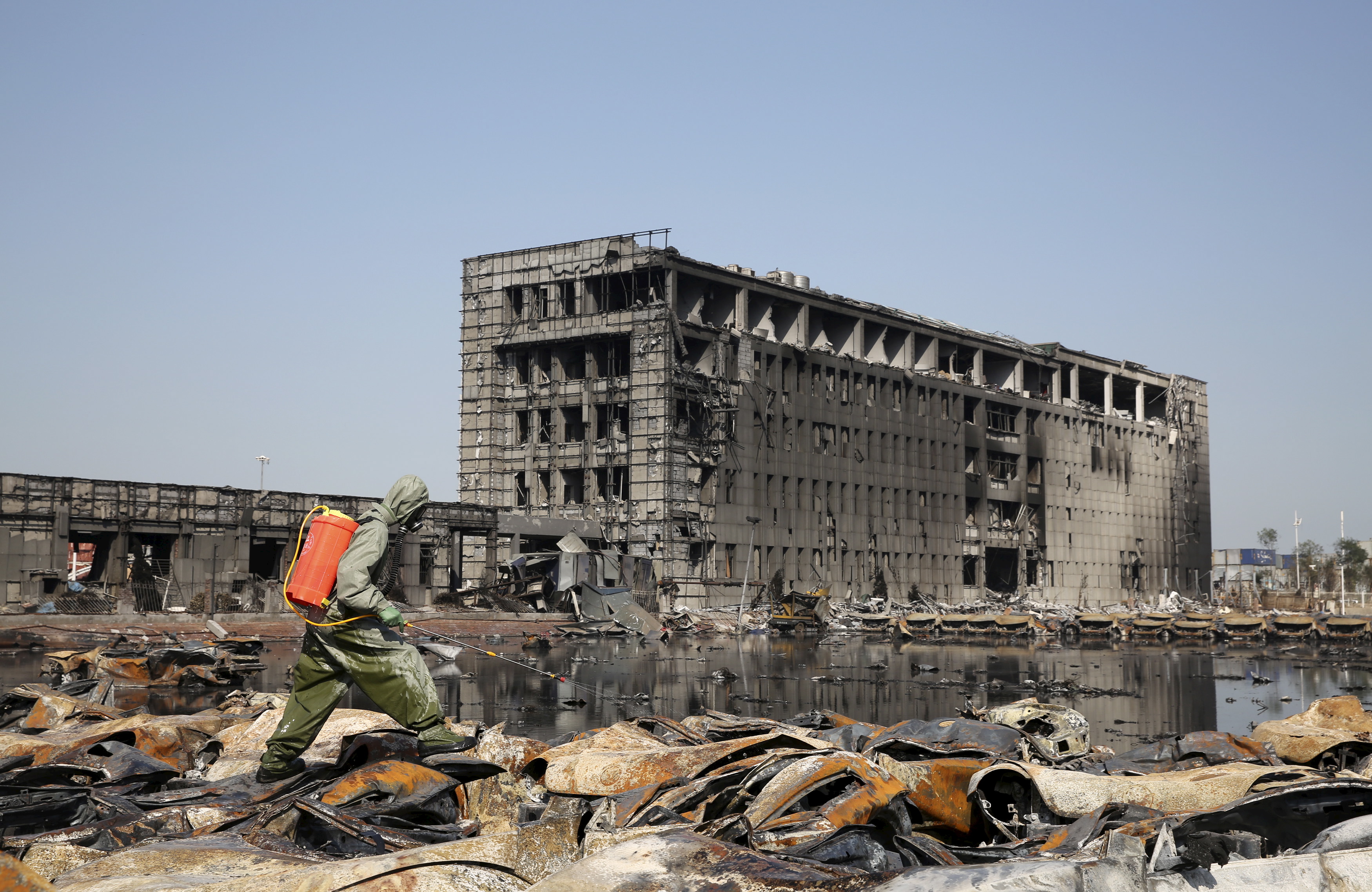 A People's Liberation Army (PLA) soldier of the anti-chemical warfare corps sprays liquid on the debris at the site of last week's blasts in Binhai new district of Tianjin, China, Aug. 21, 2015.