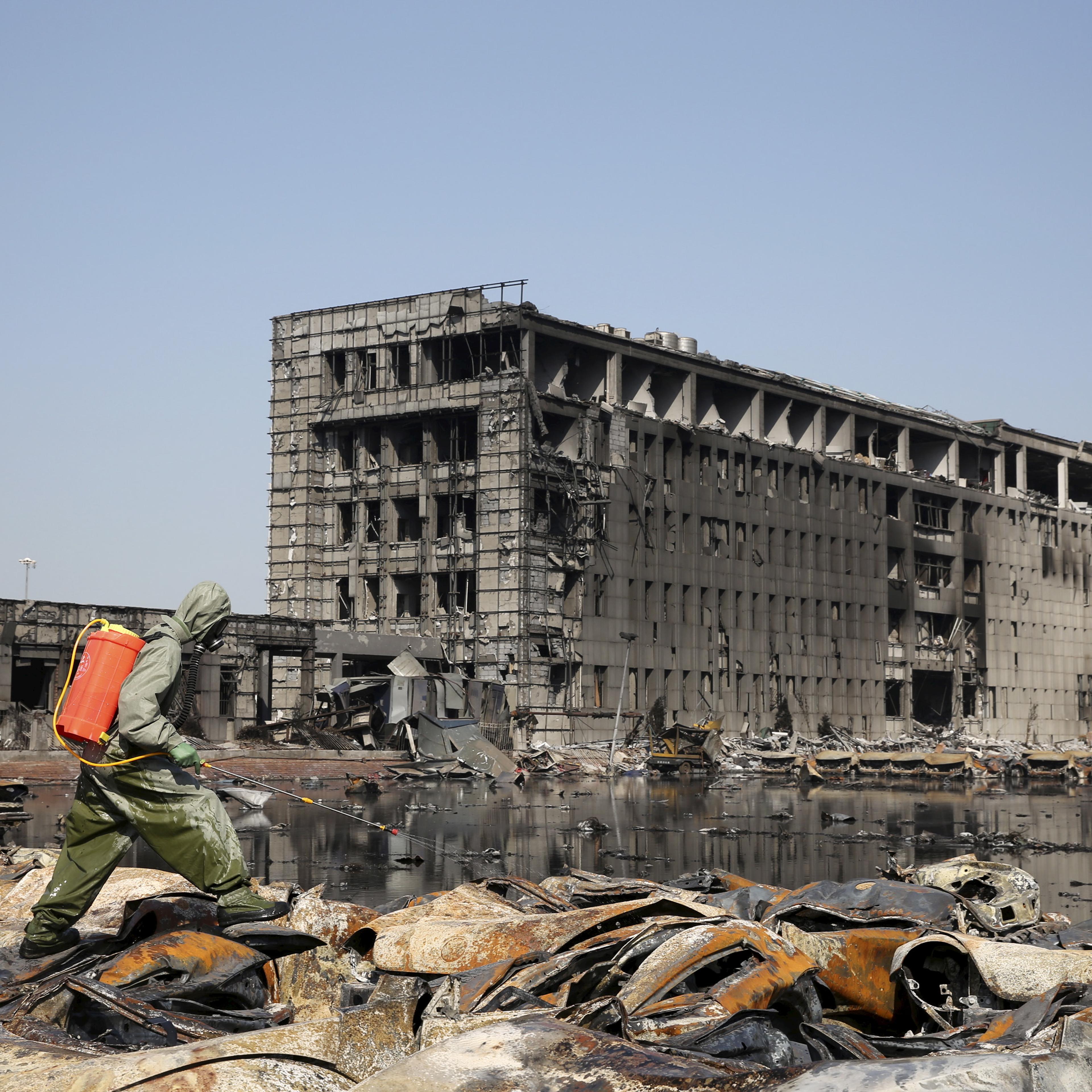 A People's Liberation Army (PLA) soldier of the anti-chemical warfare corps sprays liquid on the debris at the site of last week's blasts in Binhai new district of Tianjin, China, Aug. 21, 2015.