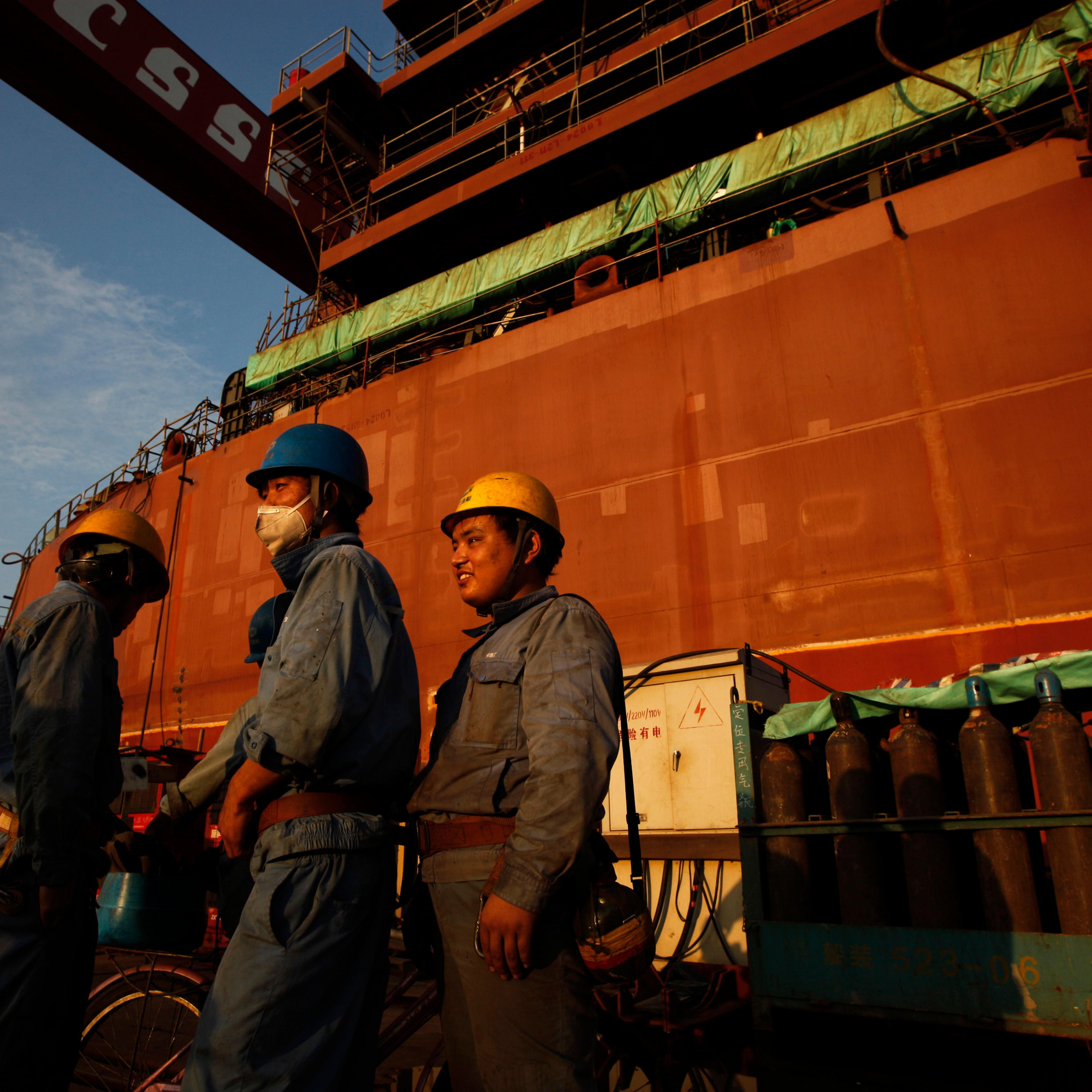Employees stand in front of nearly completed ship at China State Shipbuilding Corporation (CSSC) Longxue shipbuilding ,in the southern Chinese city of Guangzhou