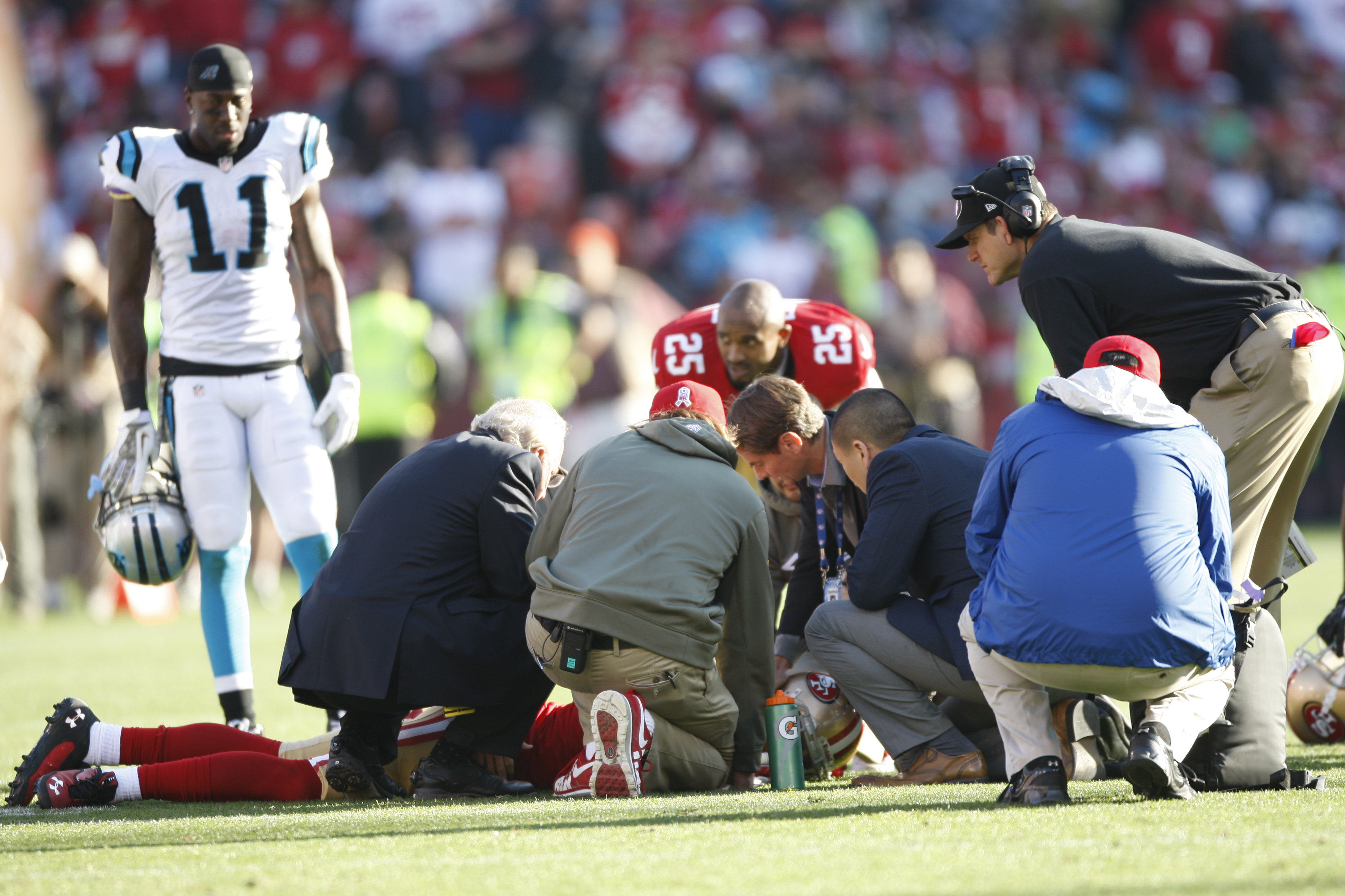 From left: Head Coach Jim Harbaugh of the San Francisco 49ers and the medical staff check out Eric Reid after he received a concussion during the game against the Carolina Panthers on November 10, 2013 in San Francisco, California.