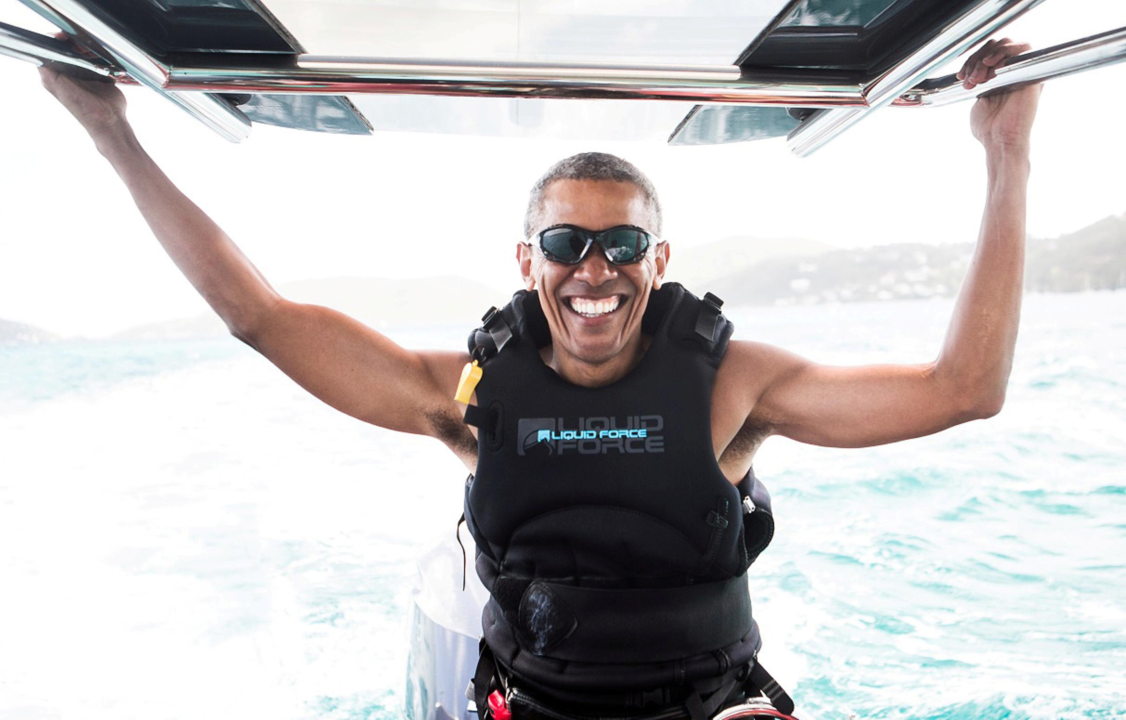 Former U.S. President Barack Obama sits on a boat during a kite surfing outing with British businessman Richard Branson during his holiday on Branson's Moskito island in the British Virgin Islands