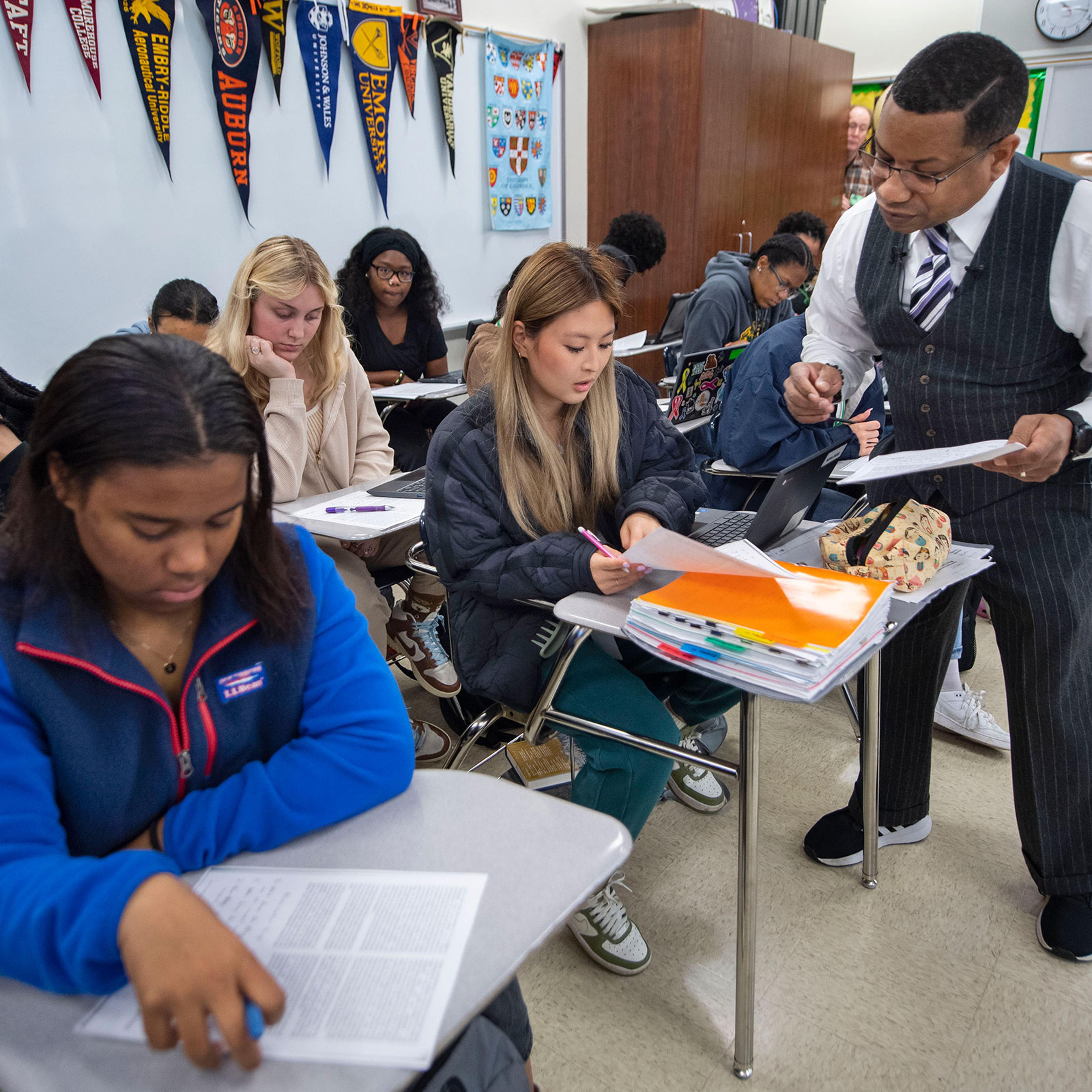 Baton Rouge Magnet High School teacher Emmitt Glynn III, right, talks with Neena Webb, 17, center, in class with other students including, from left, Amilya Franklin, 18, Bailey Bunch, 18, and Hannah Landry, 17, Friday, Feb. 17, 2023, as he teaches a new