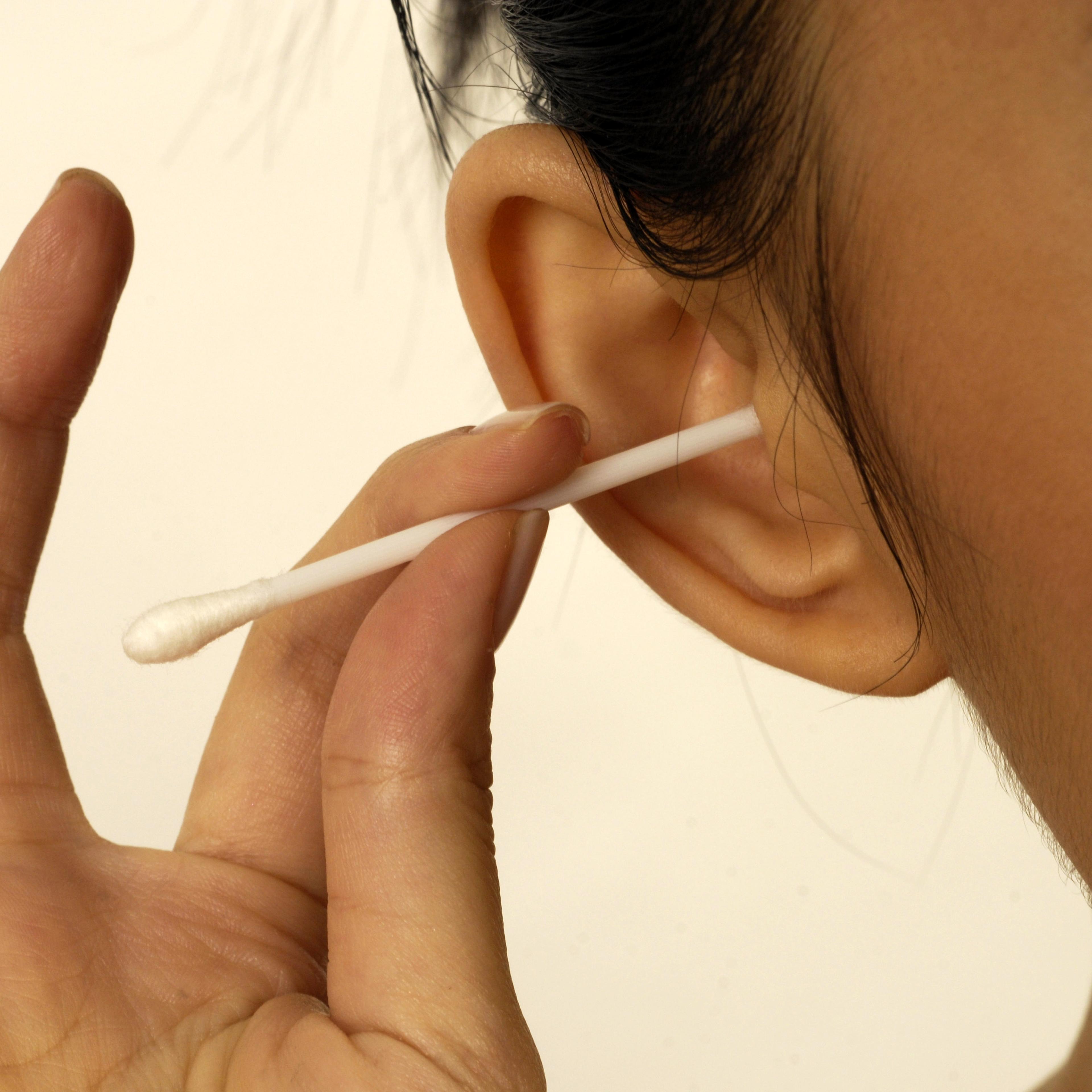 Close-up of woman cleaning her ear with cotton bud