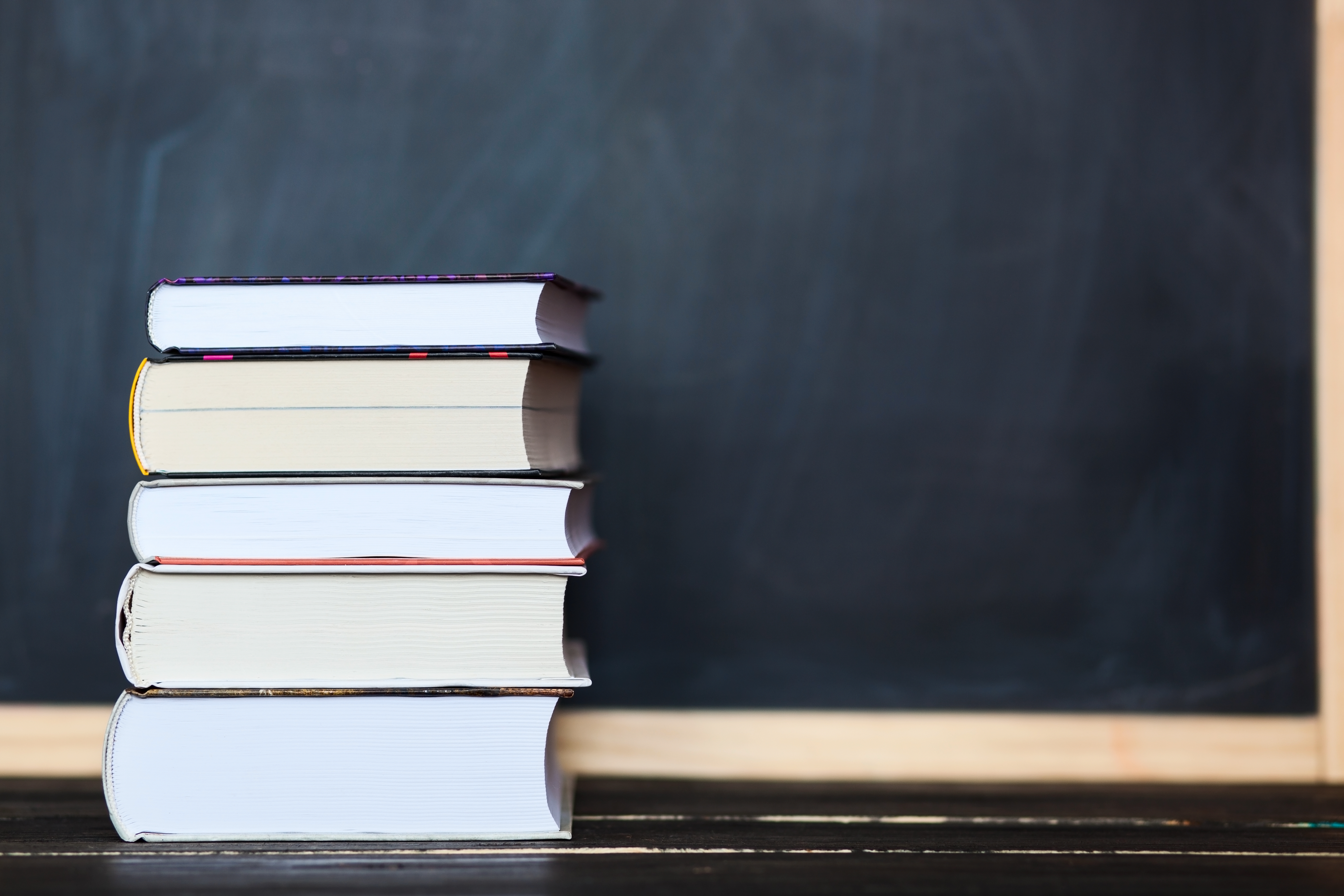 Stack of books with chalkboard in background . Space for your text
