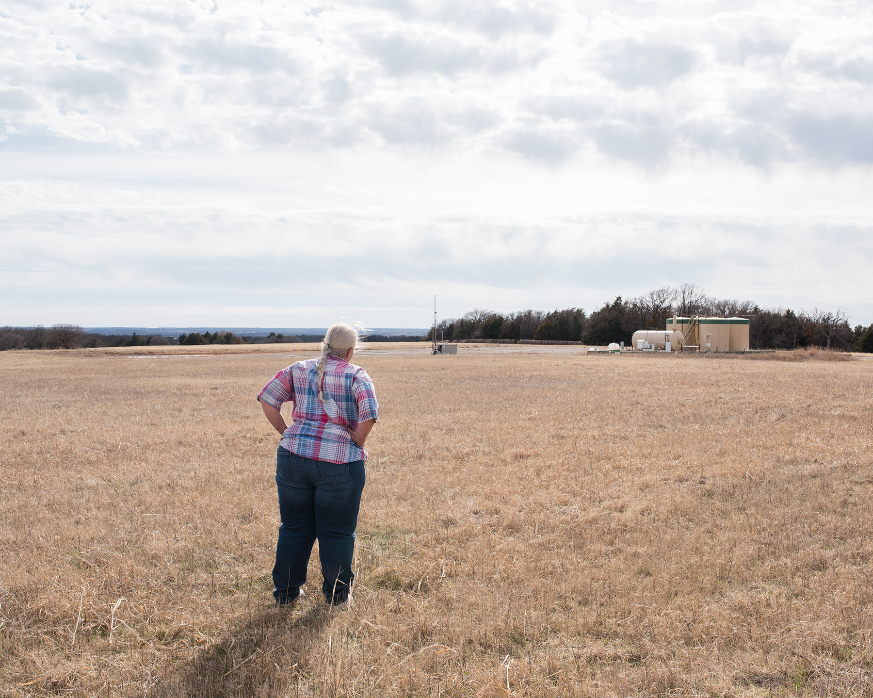 Jackie Dill, near an oil well outside her home in Coyle, says she’s felt 30 earthquakes in one day