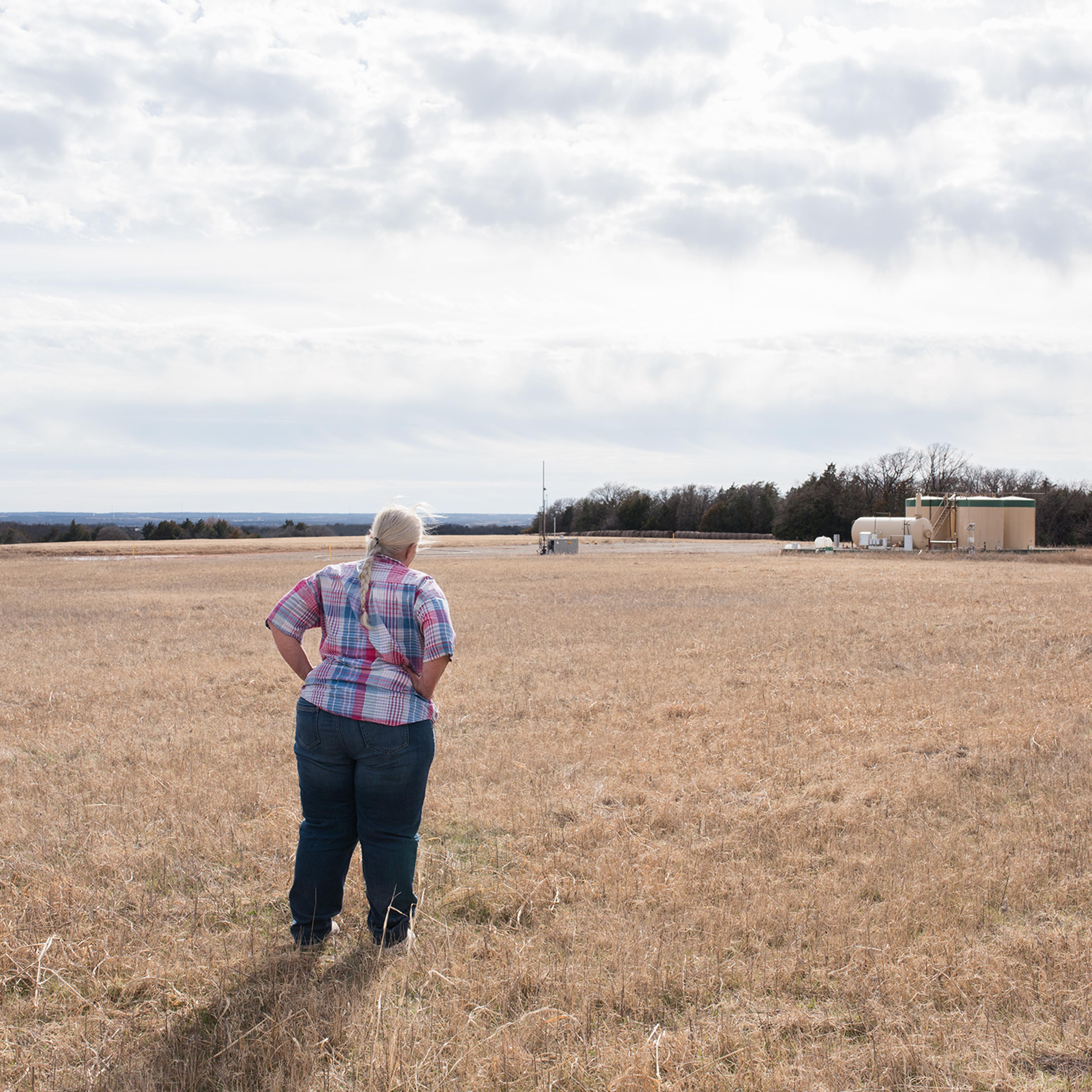 Jackie Dill, near an oil well outside her home in Coyle, says she’s felt 30 earthquakes in one day