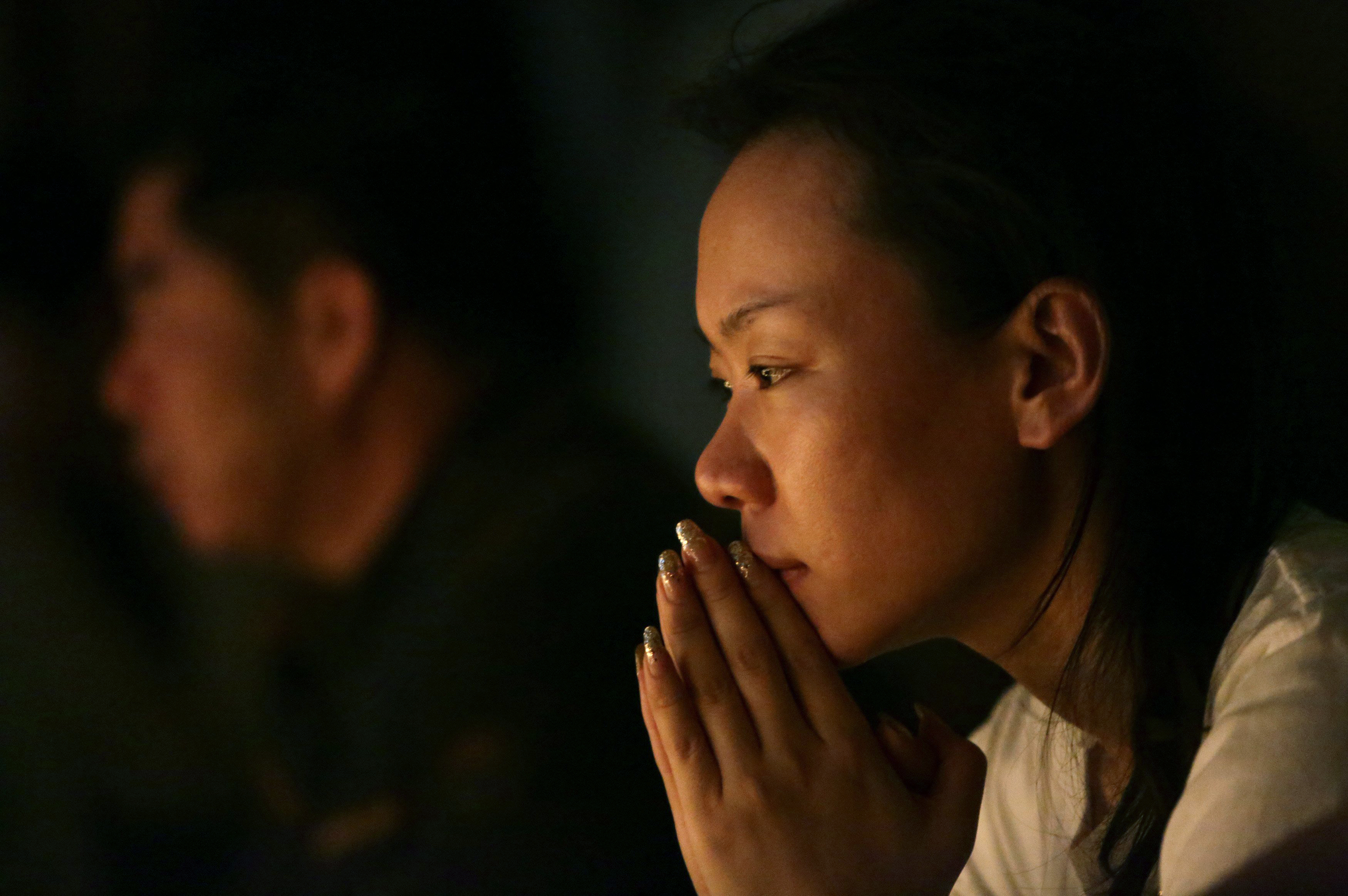 Family members pray during a candlelight vigil for passengers onboard the missing Malaysia Airlines Flight MH370 in the early morning, at Lido Hotel, in Beijing on April 8, 2014.
