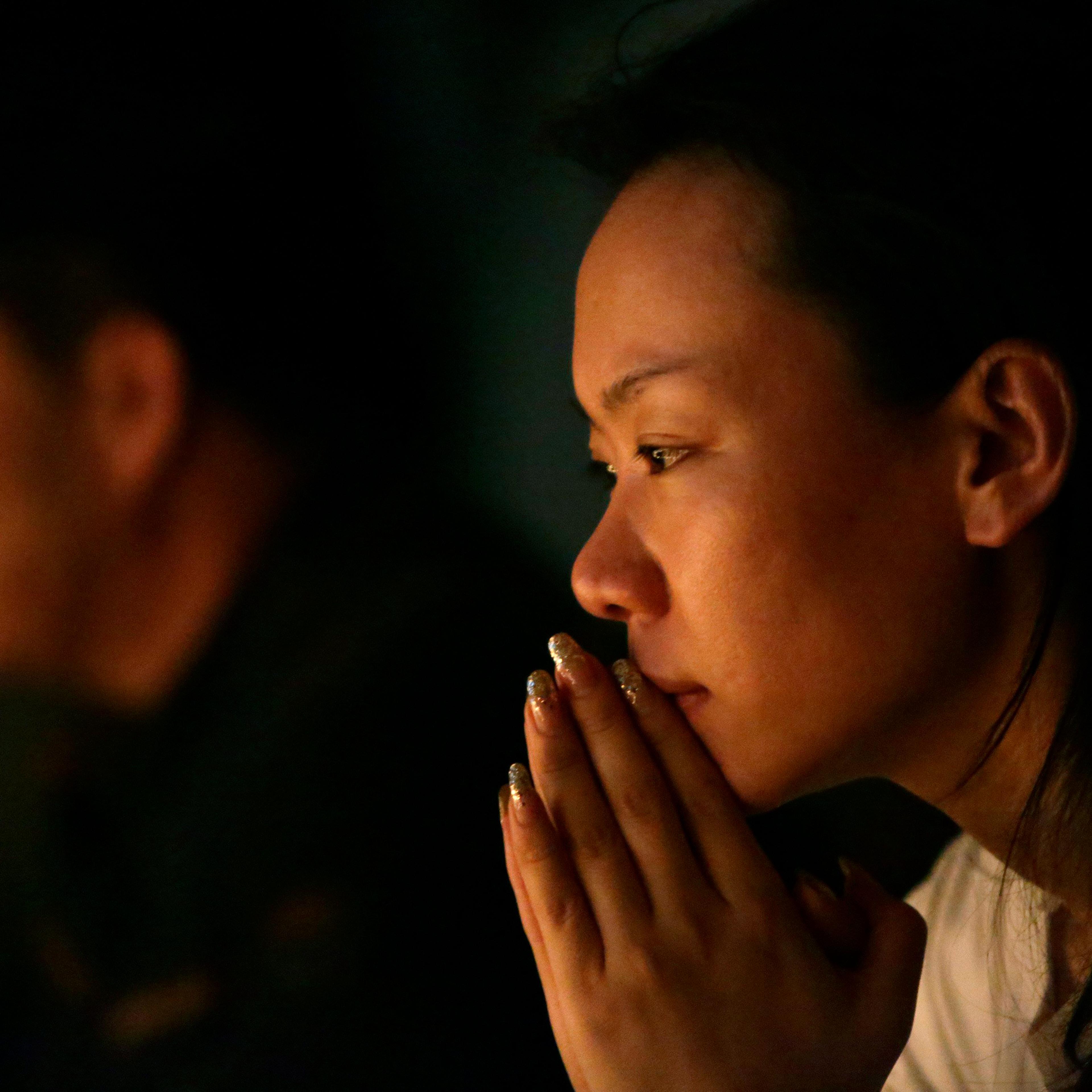 Family members pray during a candlelight vigil for passengers onboard the missing Malaysia Airlines Flight MH370 in the early morning, at Lido Hotel, in Beijing on April 8, 2014.