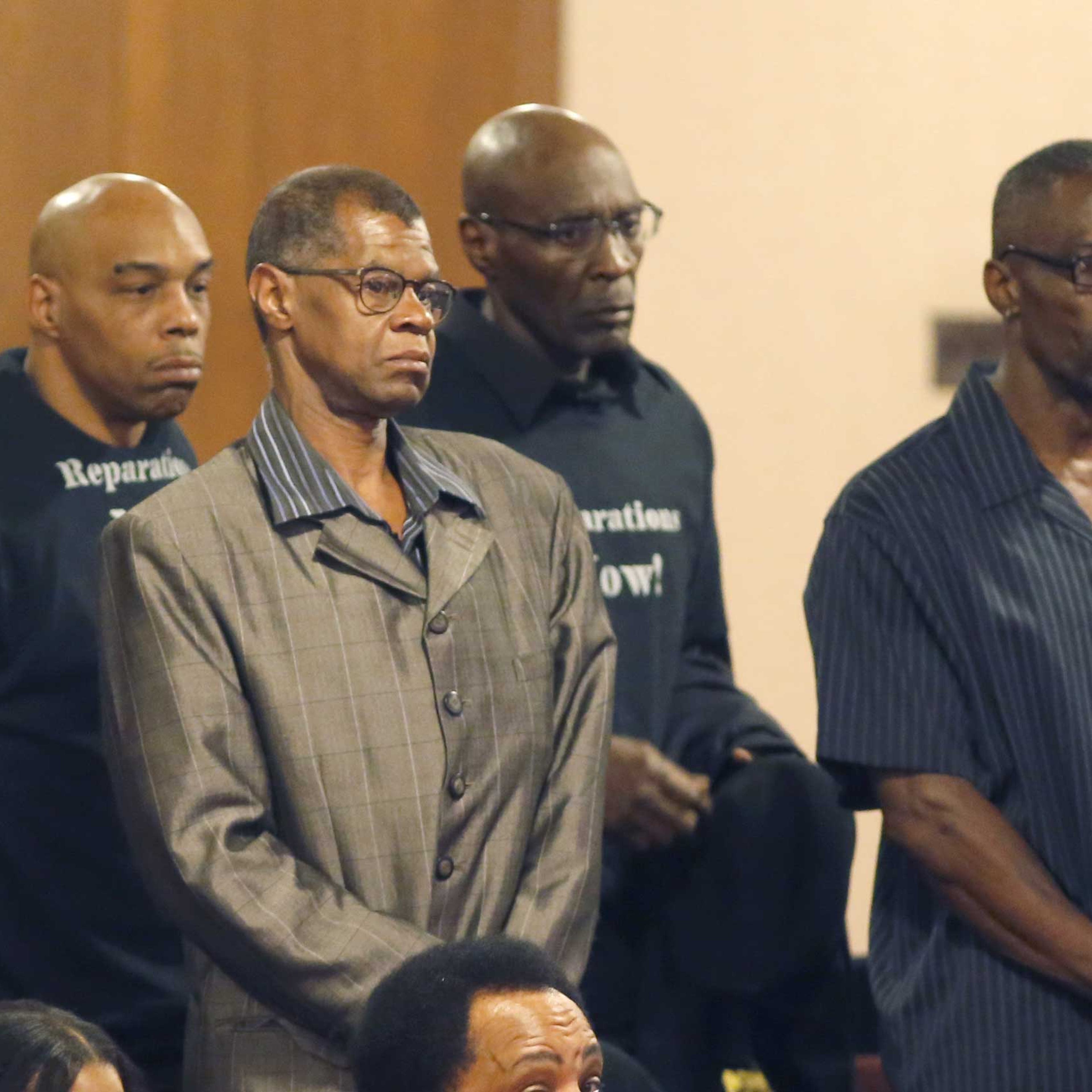Men identified as victims of police torture under the command of retired Chicago Police Commander Jon Burge, stand to be recognized by the Chicago City Council city council, May 6, 2015, in Chicago.