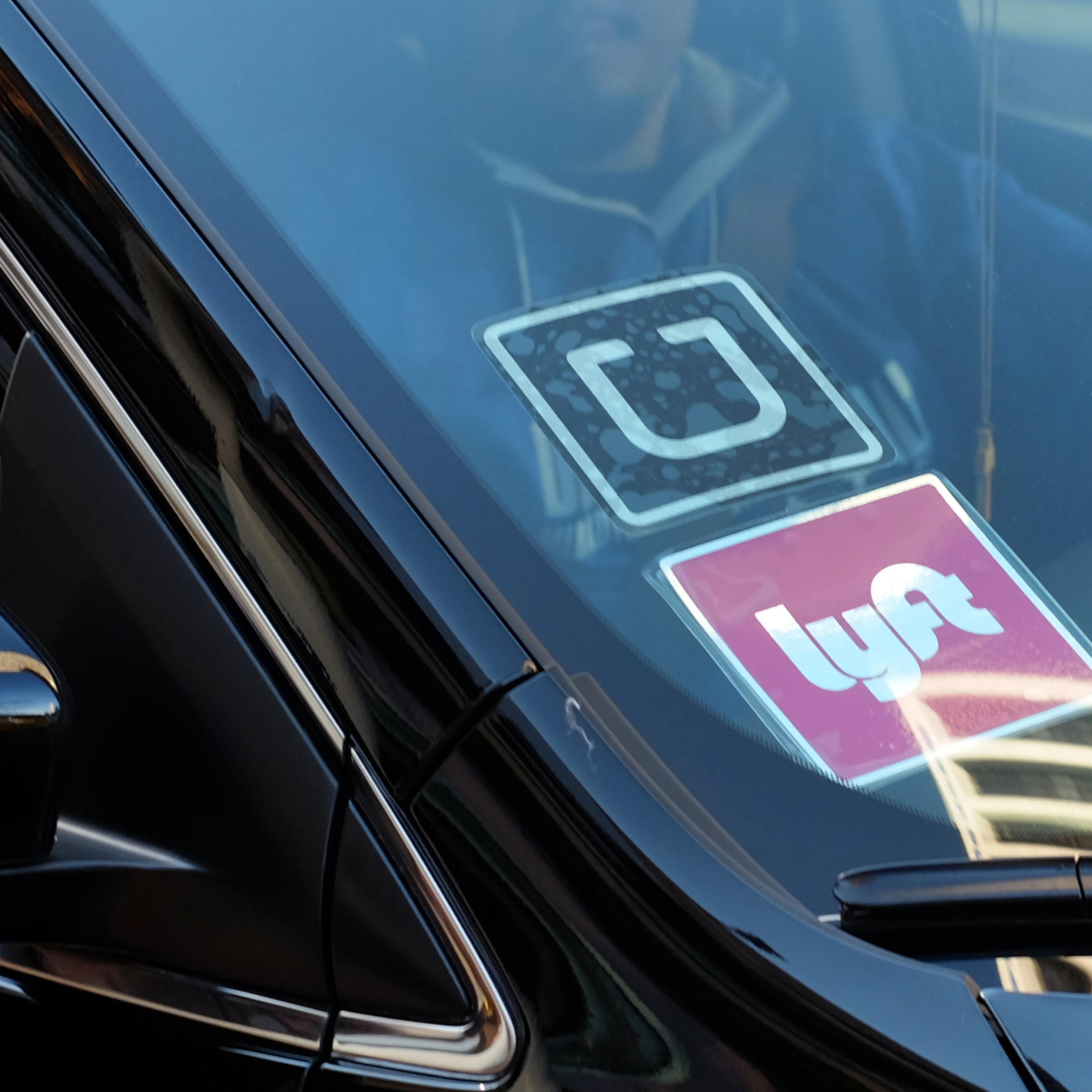 Los Angeles Lyft and UberA driver displaying Lyft and Uber stickers on his front windshield drops off a fare in downtown Los Angeles, Calif on Jan. 12, 2016.