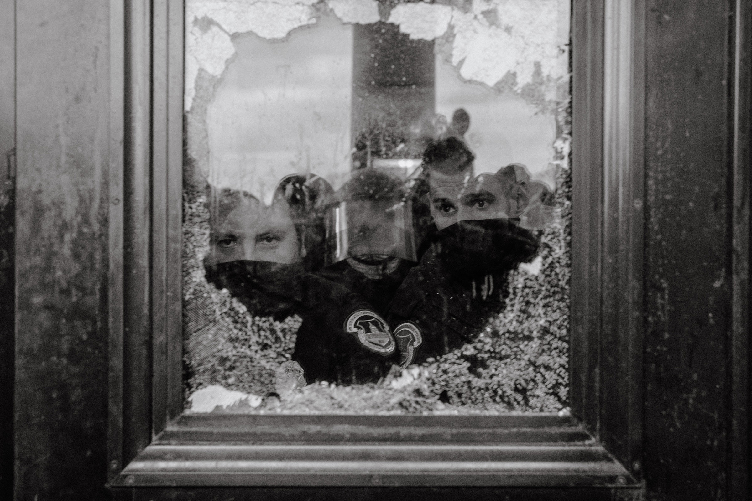 U.S. Capitol Police officers watch a mob of supporters for President Donald Trump through a partially broken window of the U.S. Capitol Building in Washington on Jan. 6, 2021.