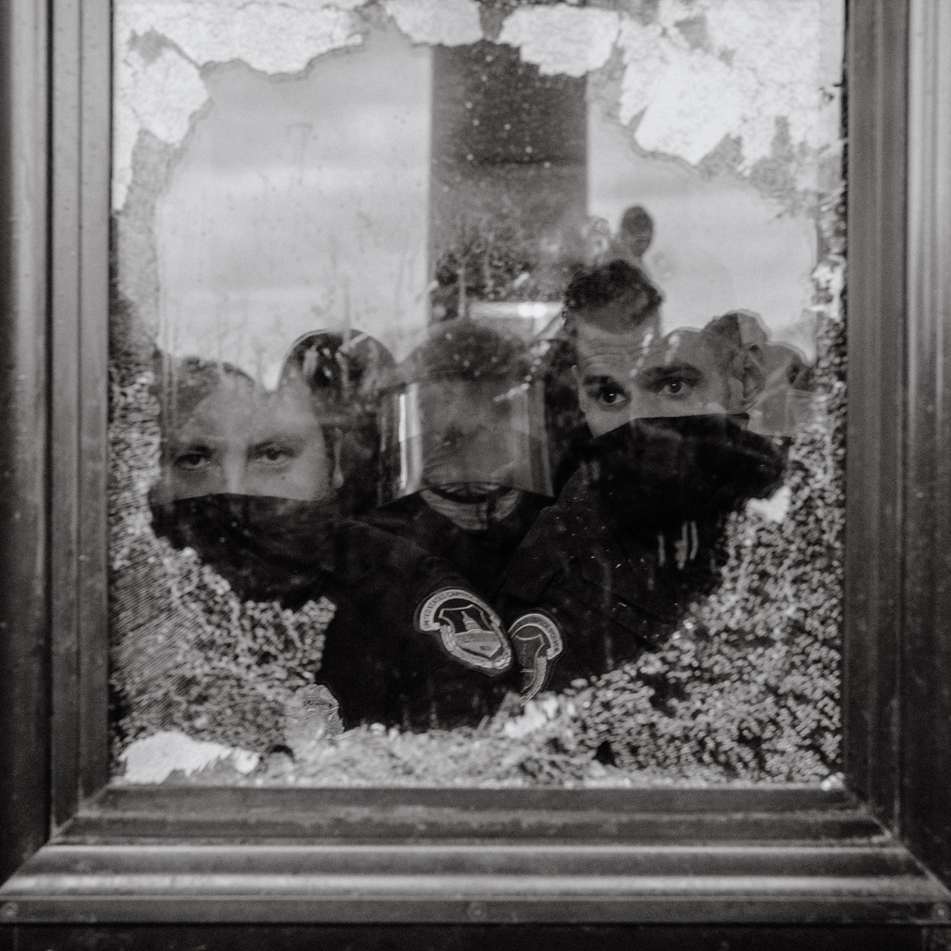 U.S. Capitol Police officers watch a mob of supporters for President Donald Trump through a partially broken window of the U.S. Capitol Building in Washington on Jan. 6, 2021.