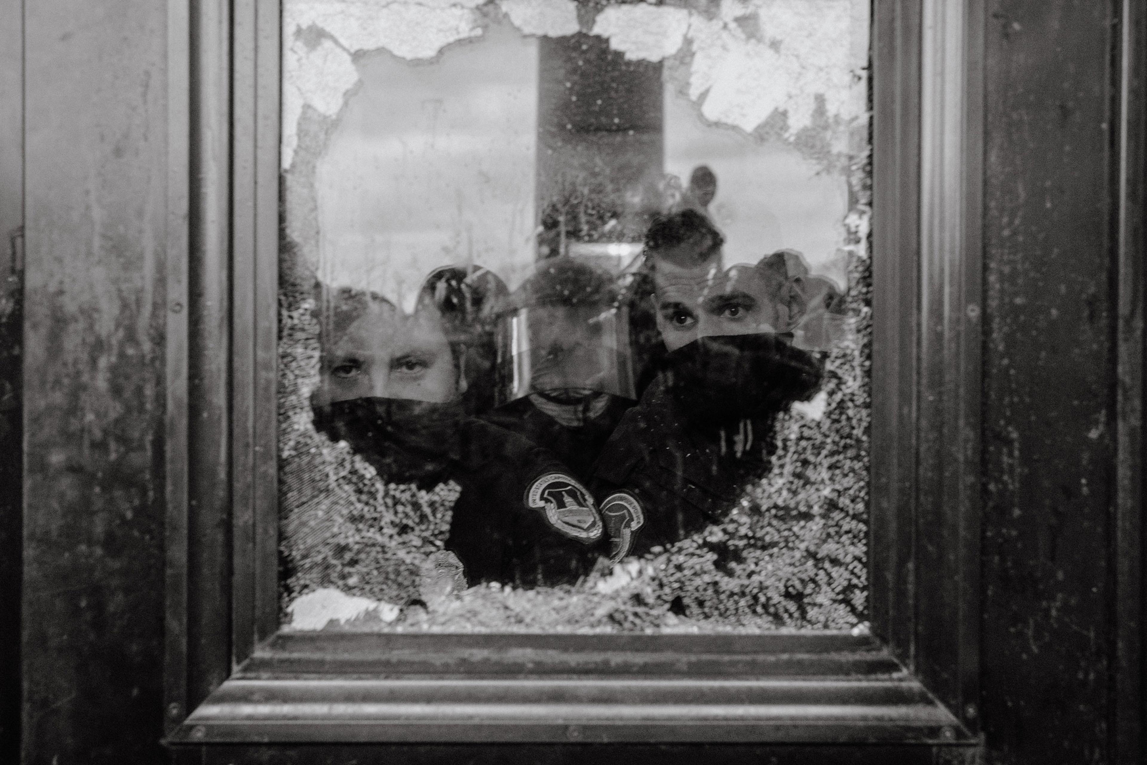 U.S. Capitol Police officers watch a mob of supporters for President Donald Trump through a partially broken window of the U.S. Capitol Building in Washington on Jan. 6, 2021.