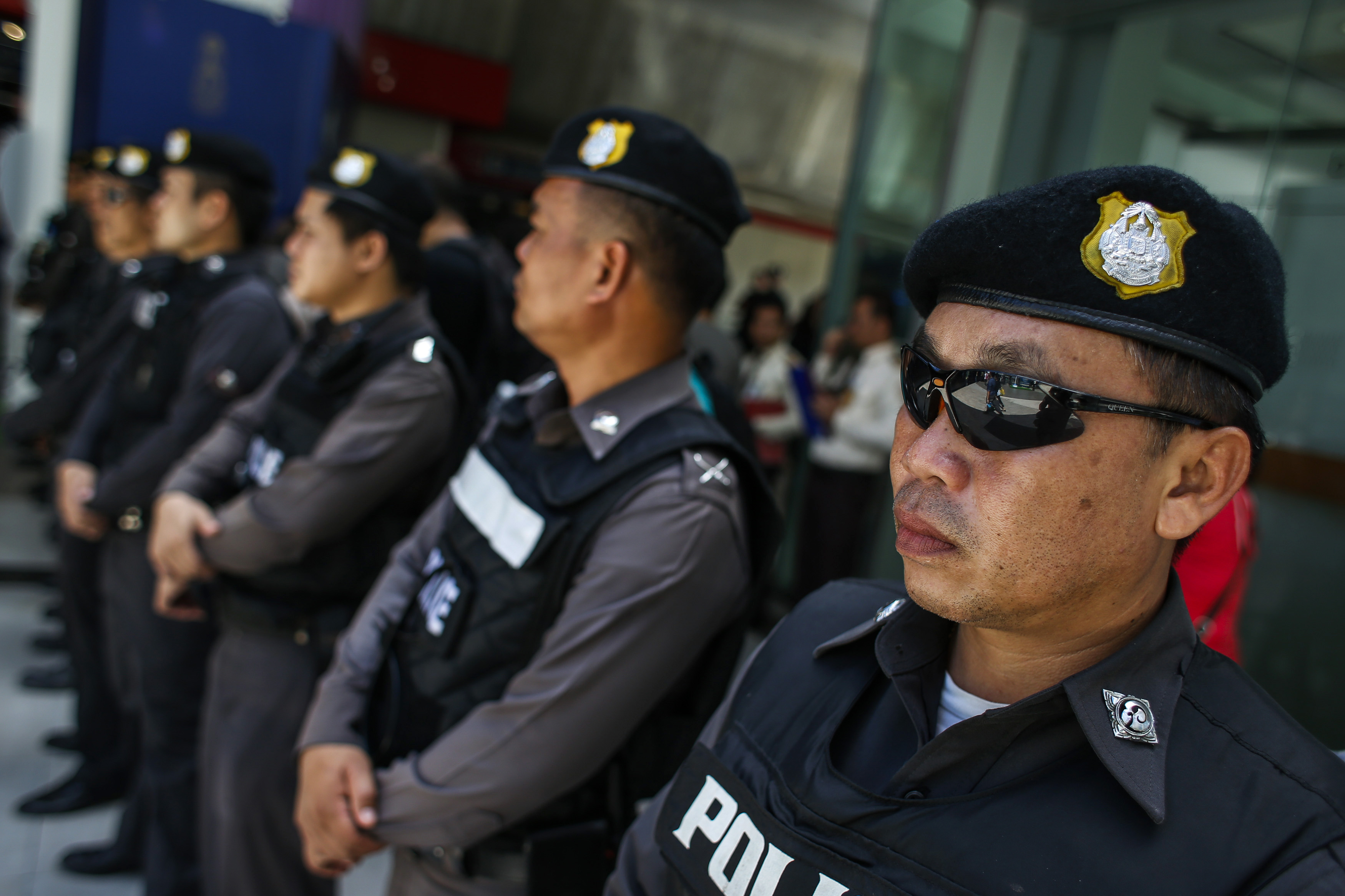 Police officers stand guard at a shopping mall in Bangkok