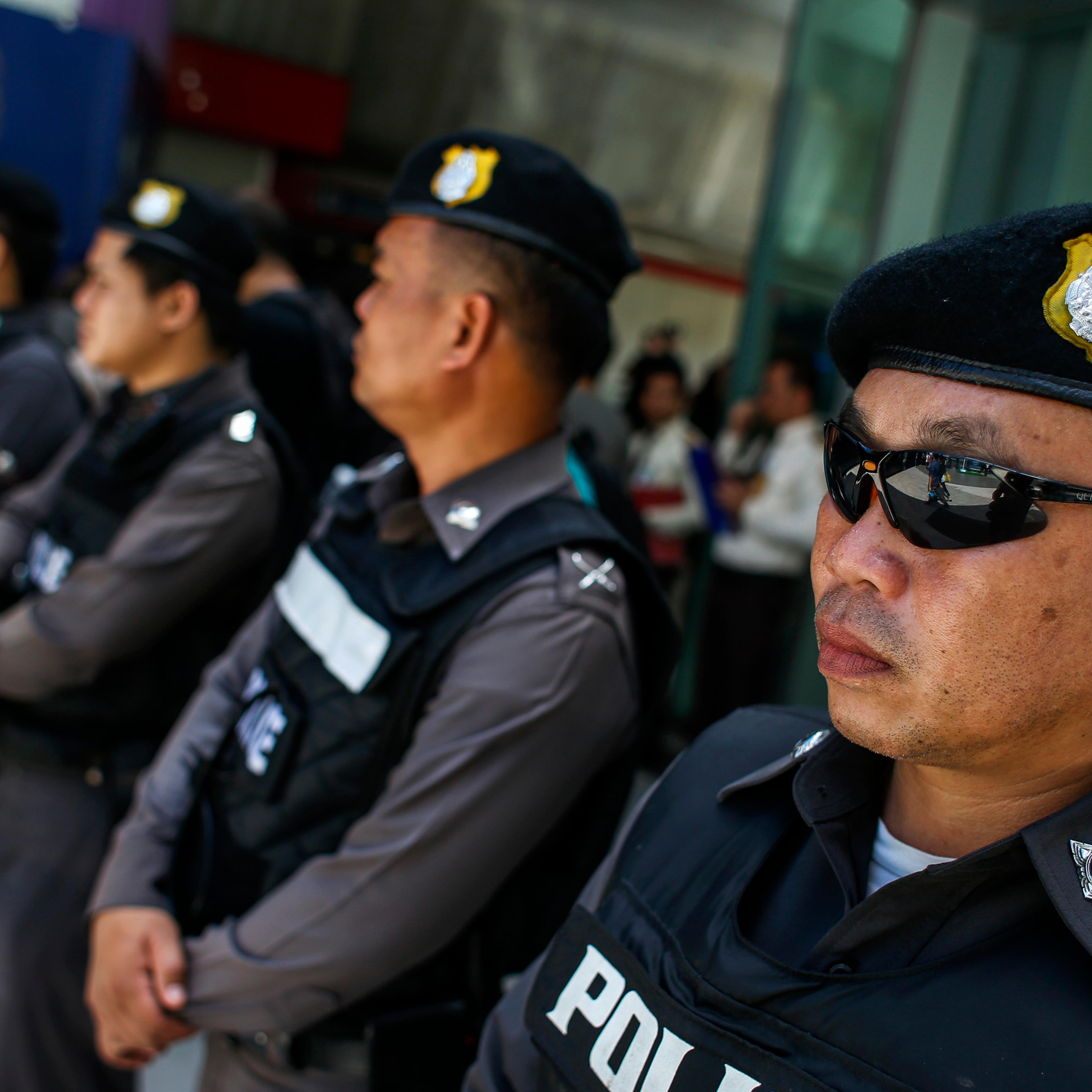 Police officers stand guard at a shopping mall in Bangkok