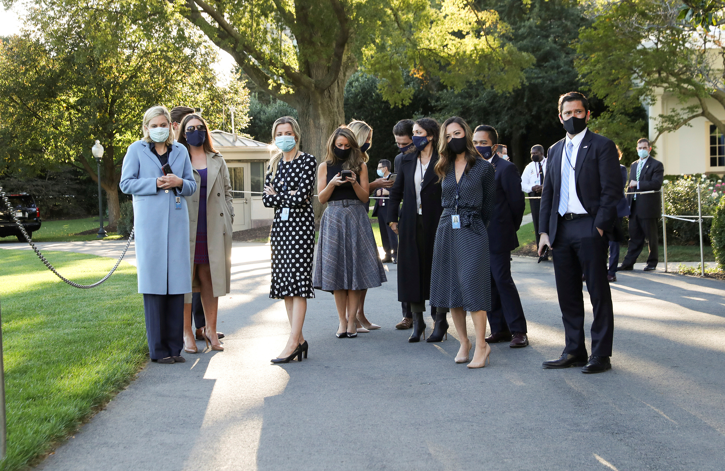 White House staff members wait to watch President Trump depart by helicopter for Walter Reed National Military Medical Center on Oct. 2, 2020.