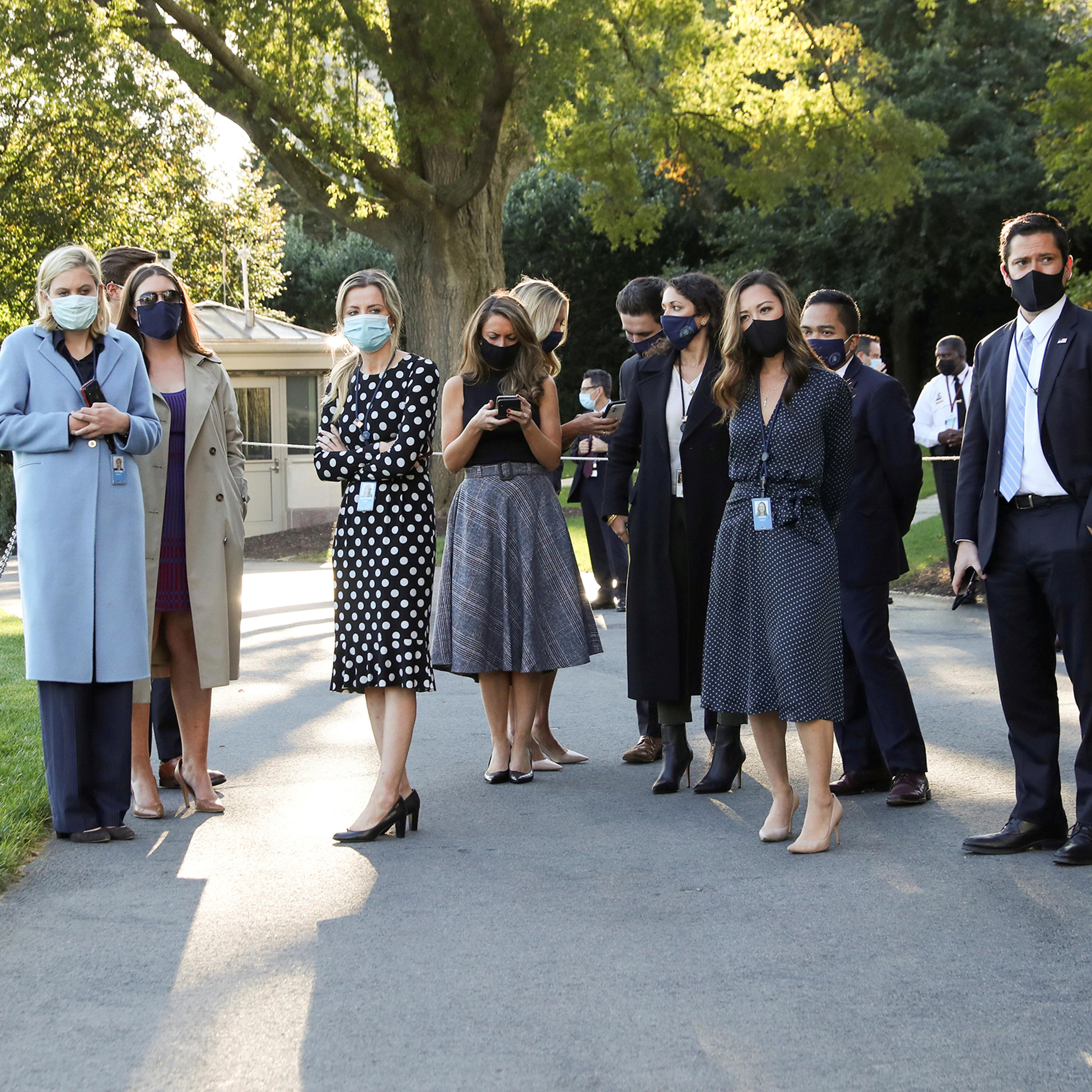 White House staff members wait to watch President Trump depart by helicopter for Walter Reed National Military Medical Center on Oct. 2, 2020.