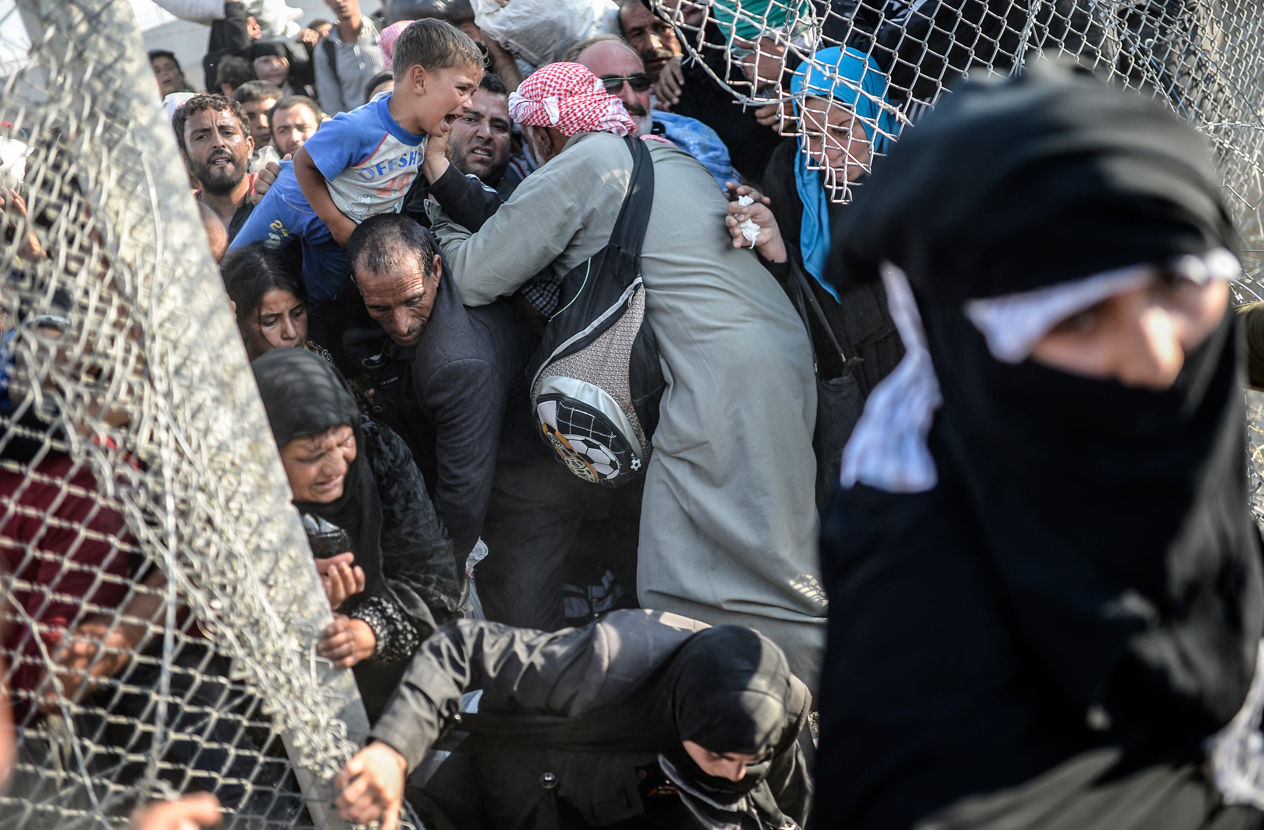 Thousands of Syrians break through the wired ripped fences, crossing from the Syrian town of Tell Abyad into Akçakale, in the Şanlıurfa province. June 14, 2015. 