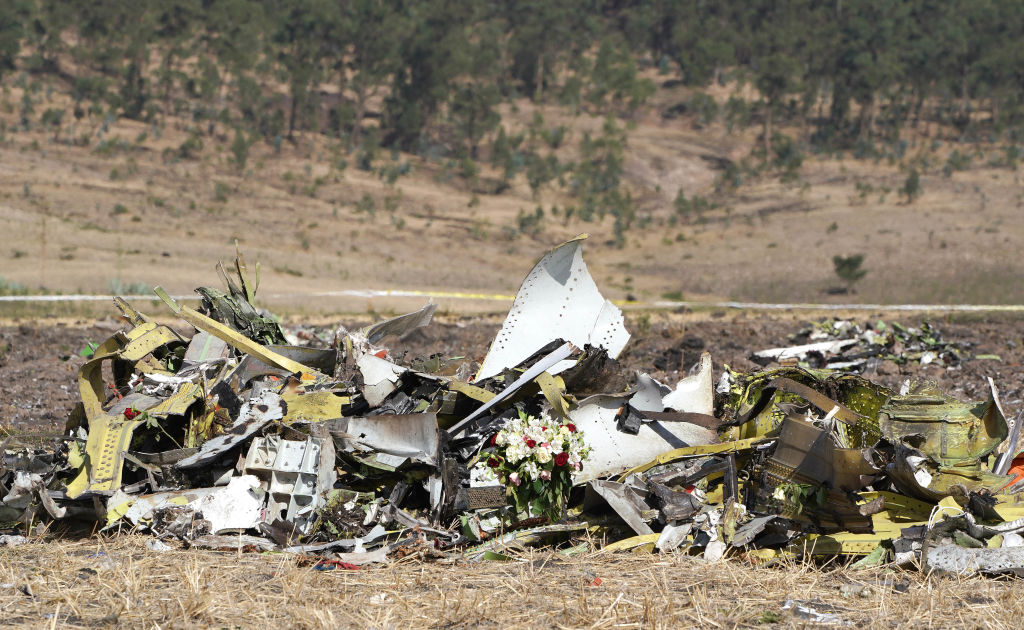 A bouquet of flowers is placed in front of a pile of debris at the scene of the Ethiopian Airlines Flight 302 crash