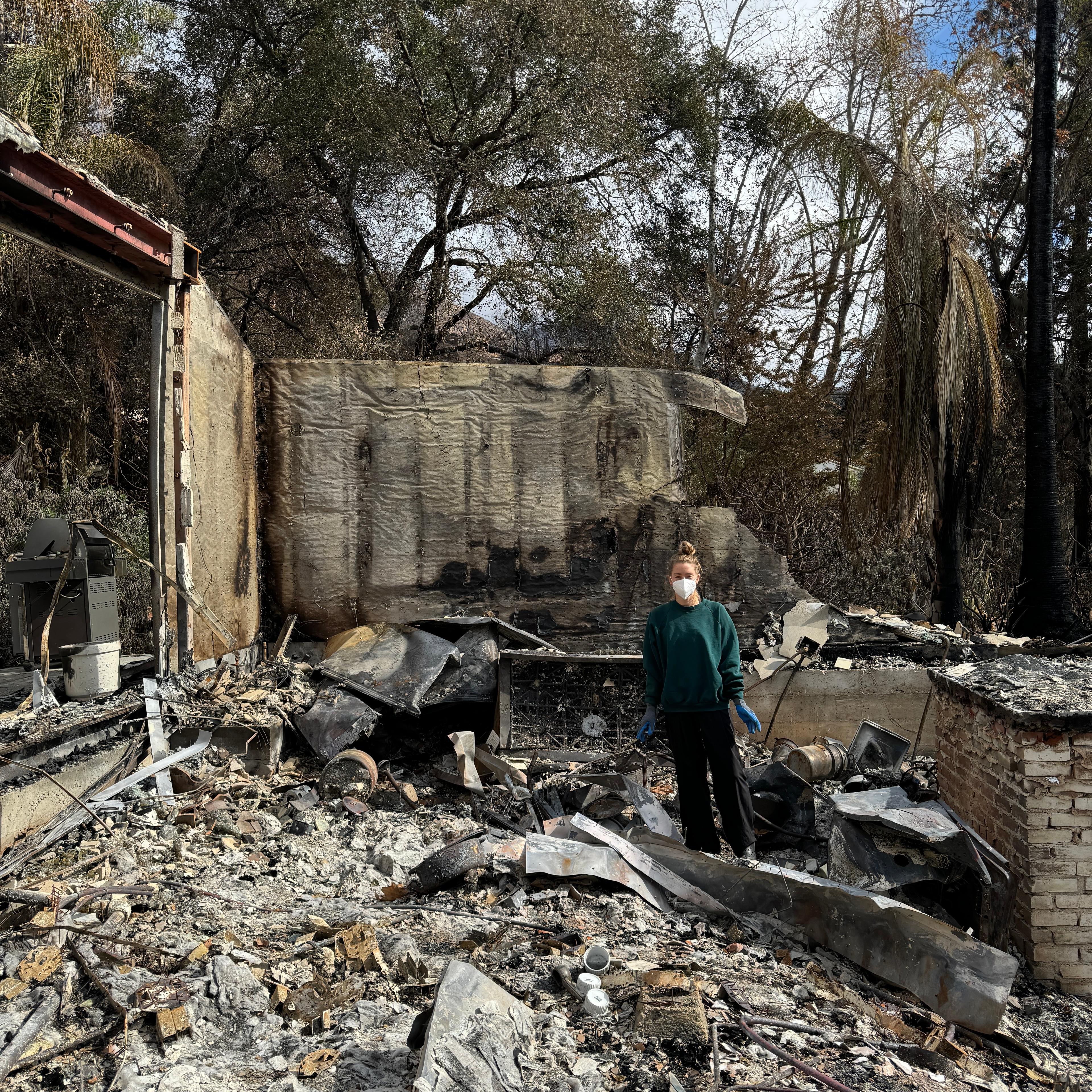 Molly stands in the rubble of her home that burned down in the Altadena fire in January 2024.