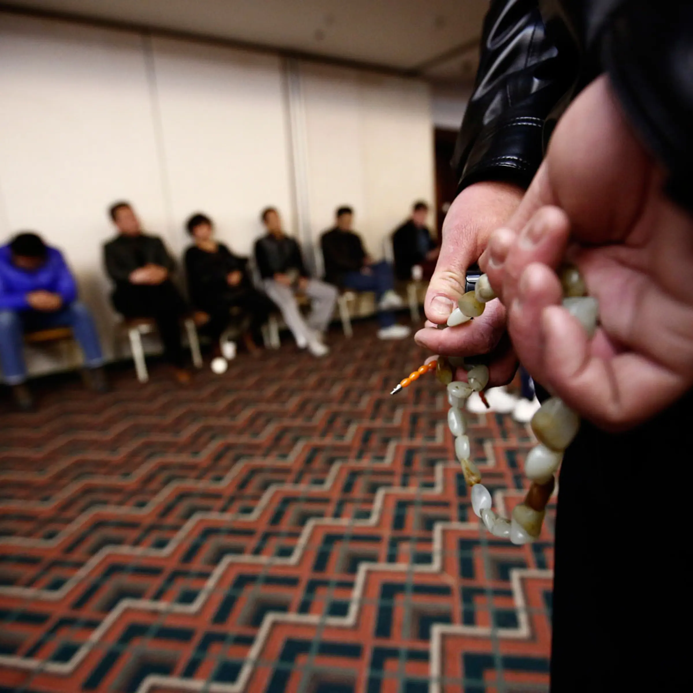 A family member of a passenger onboard the missing Malaysia Airlines flight MH370 fingers prayer beads as he listens to a briefing from the airline company with other family members (in background) at a hotel in Beijing, March 18, 2014.