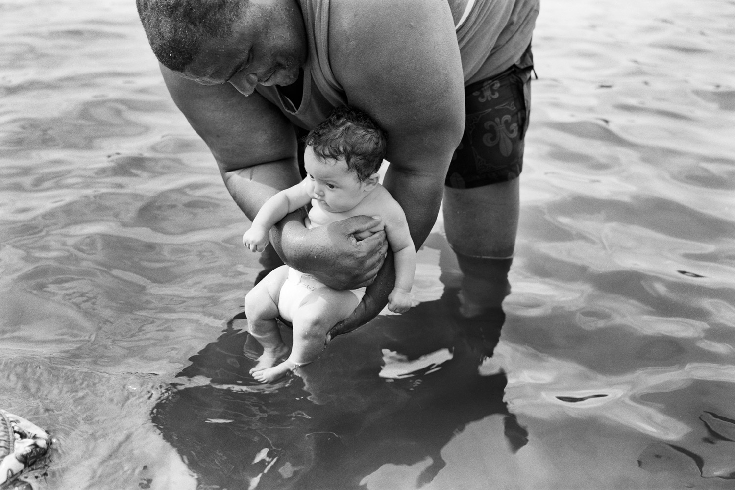 Grandfather bathes grandson in Hudson River at a beach near Troy, NY. 2010.