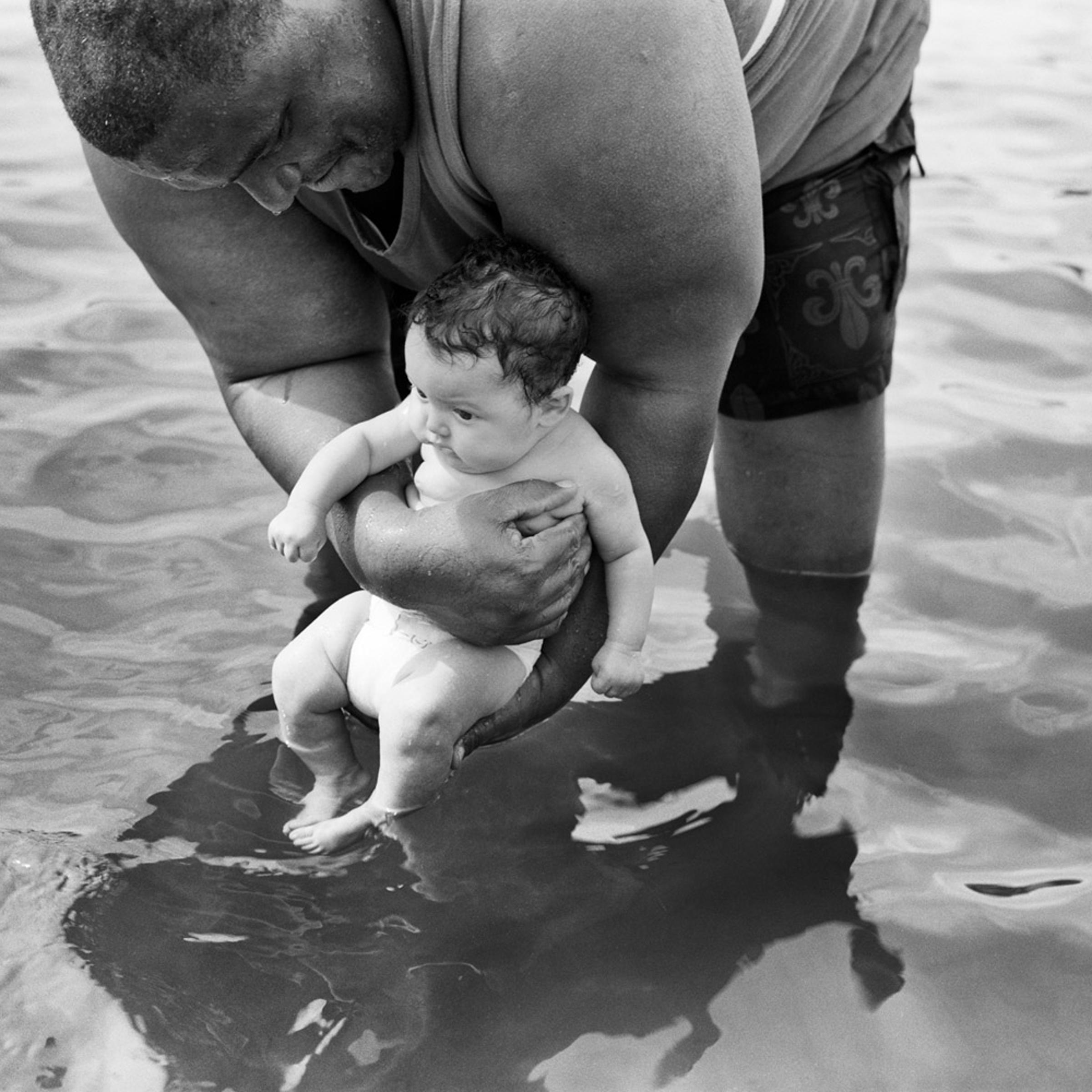 Grandfather bathes grandson in Hudson River at a beach near Troy, NY. 2010.