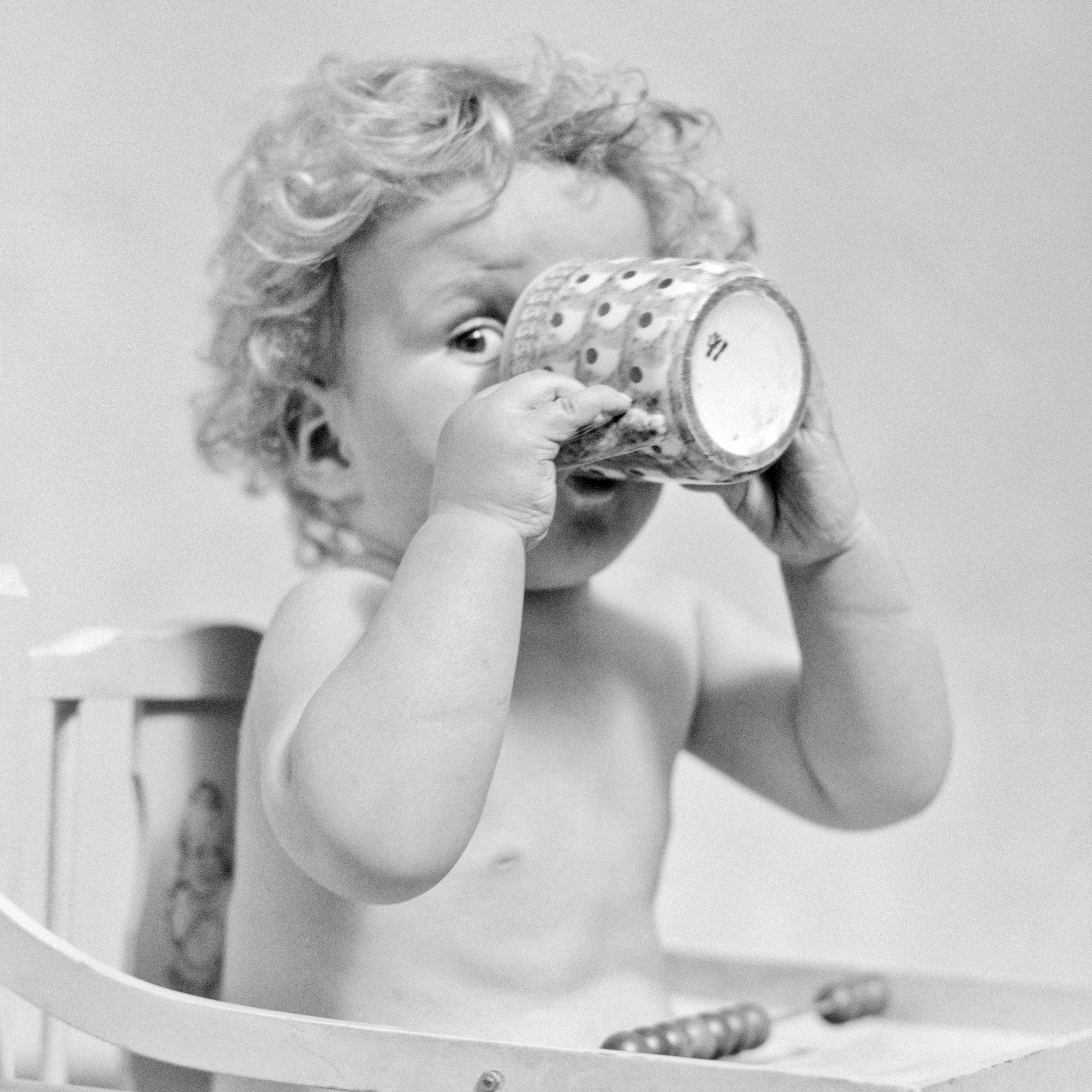 A baby boy sips from a mug