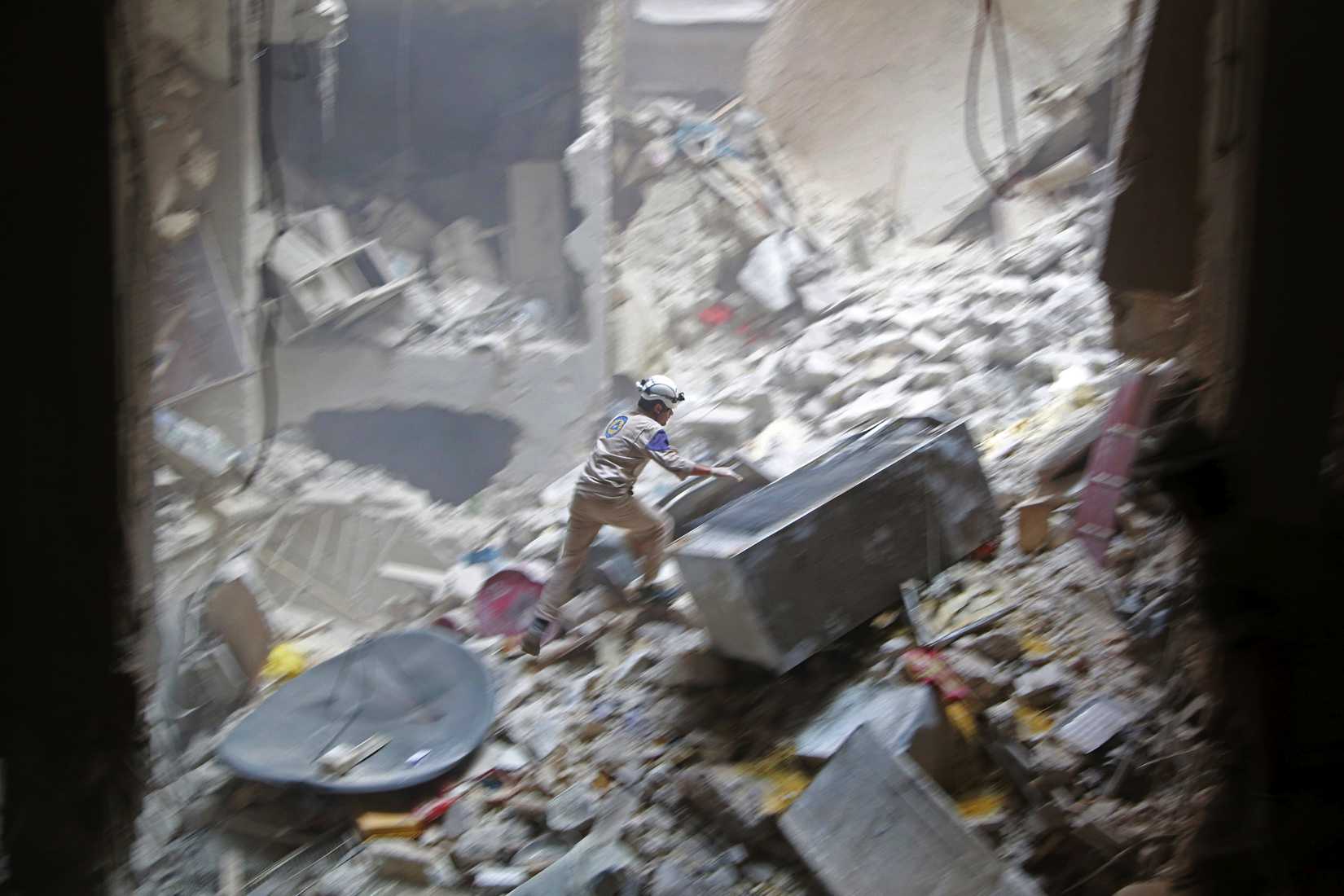 A civil-defense member looks for survivors at a site hit by what activists said were two barrel bombs dropped by forces loyal to Syria's President Bashar Assad in the Syrian city of Aleppo on July 27, 2014