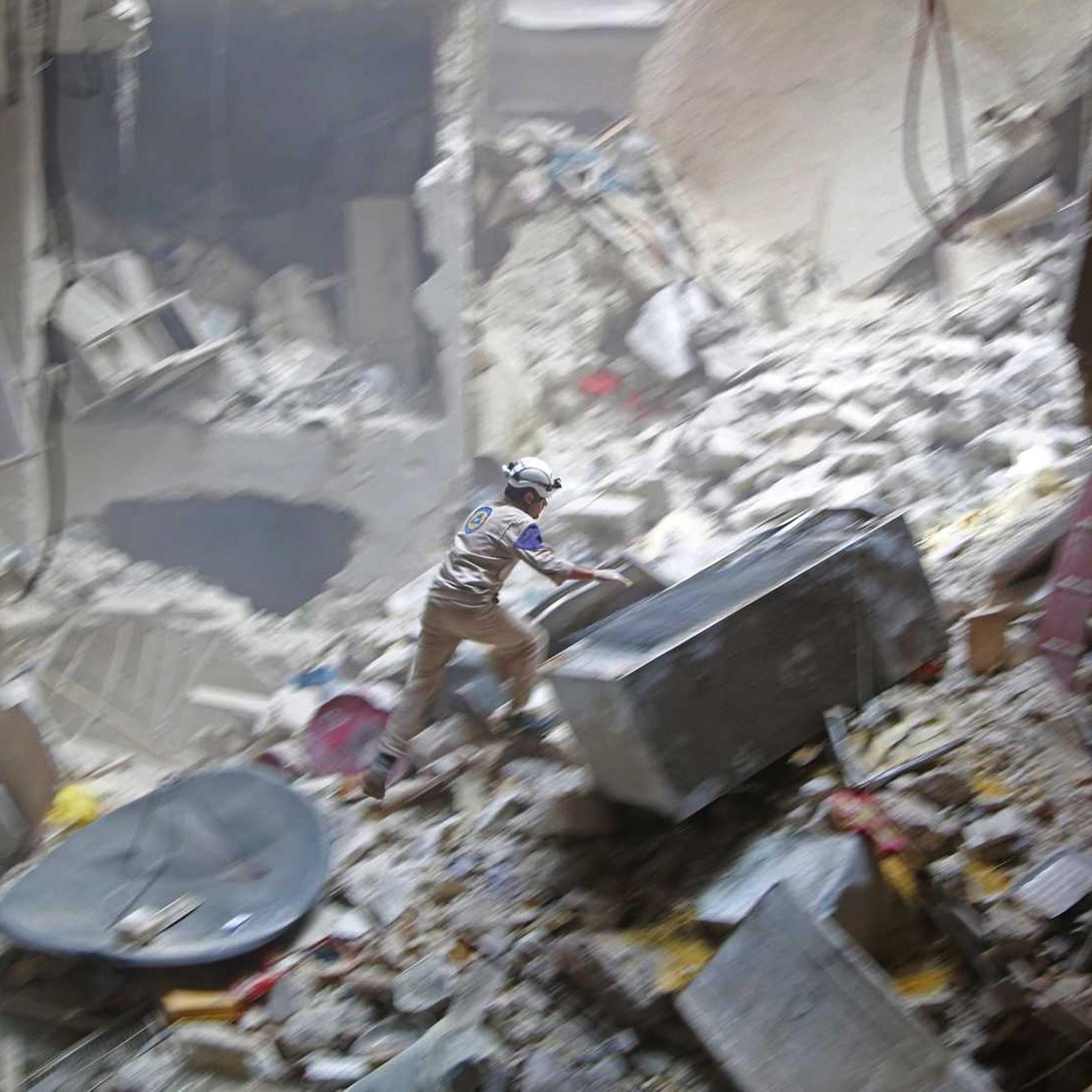 A civil-defense member looks for survivors at a site hit by what activists said were two barrel bombs dropped by forces loyal to Syria's President Bashar Assad in the Syrian city of Aleppo on July 27, 2014