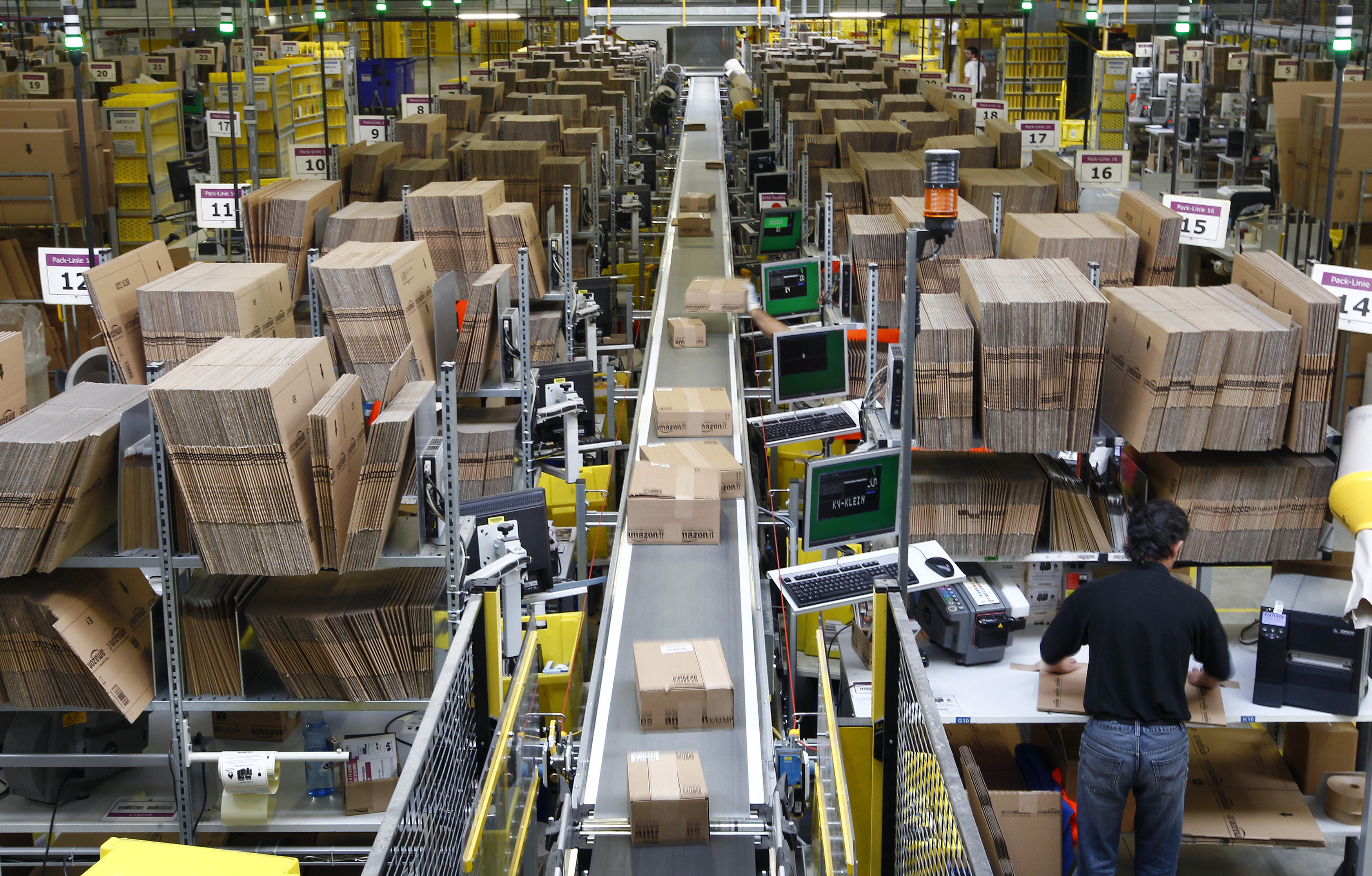 Workers pack boxes at Amazon's logistics centre in Graben