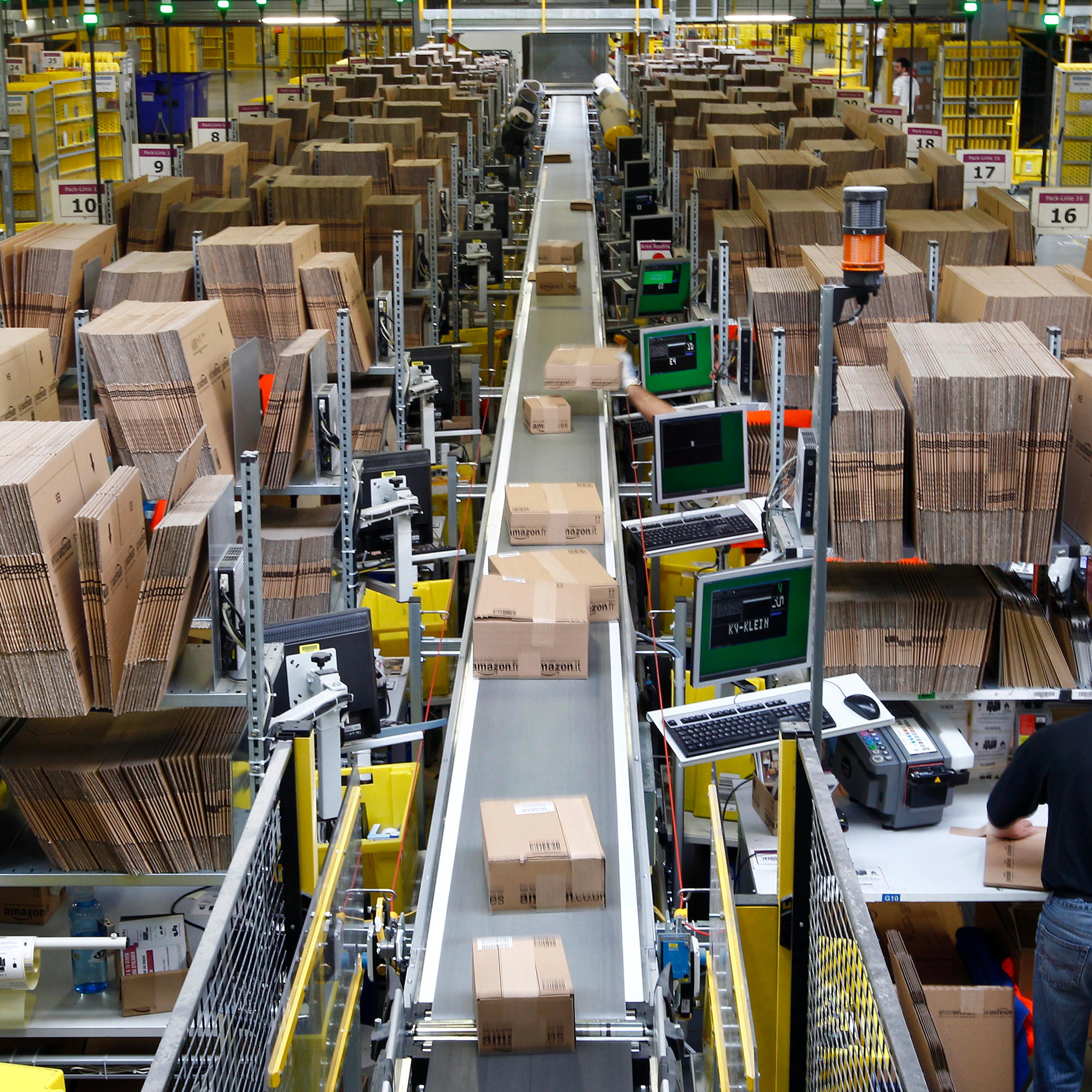 Workers pack boxes at Amazon's logistics centre in Graben