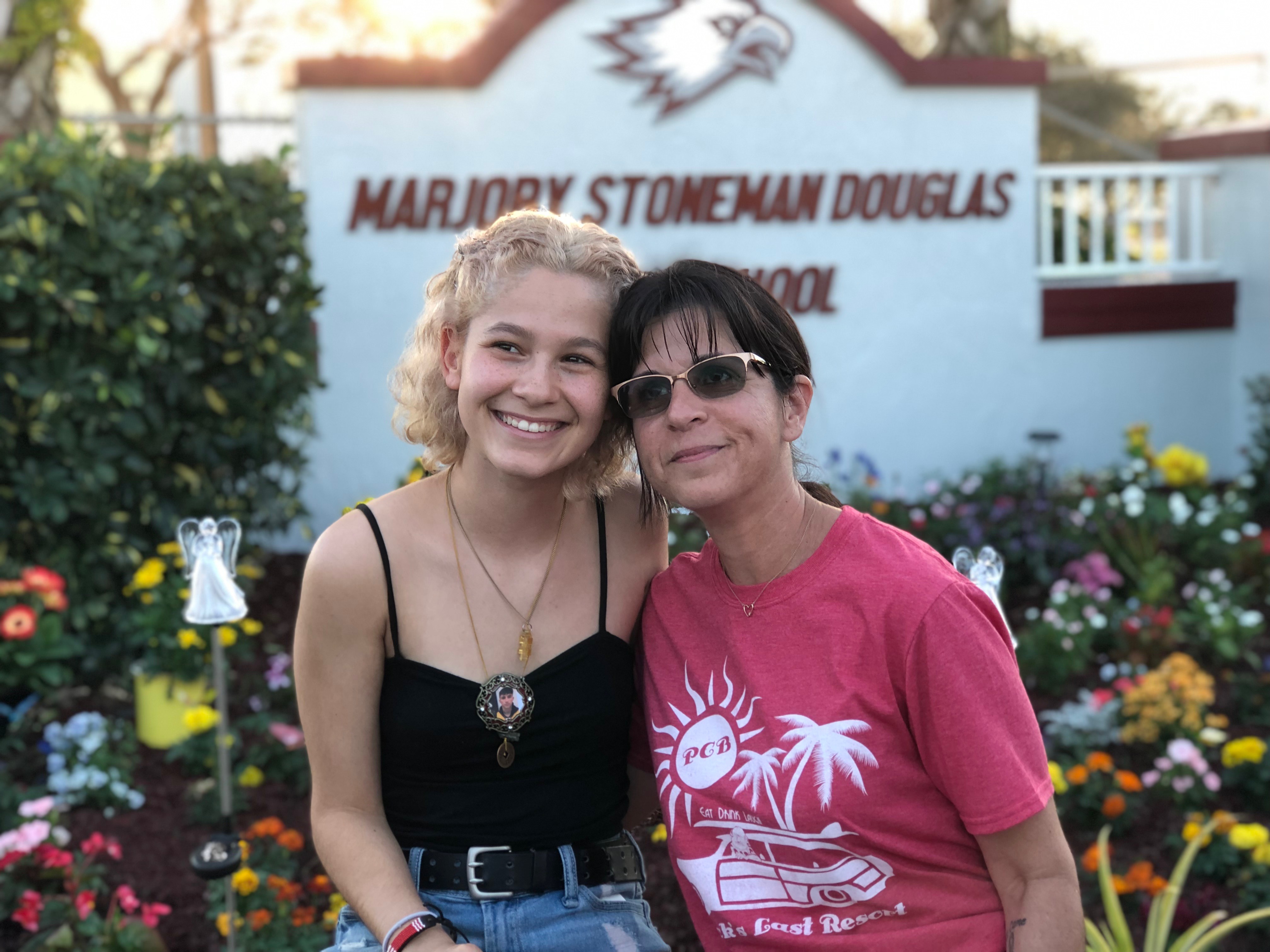 Stoneman Douglas senior Tori Gonzalez (left) and psychology teacher Ronit Reoven (right) sit in front of Project Grow Love, a garden memorial they built outside the school.