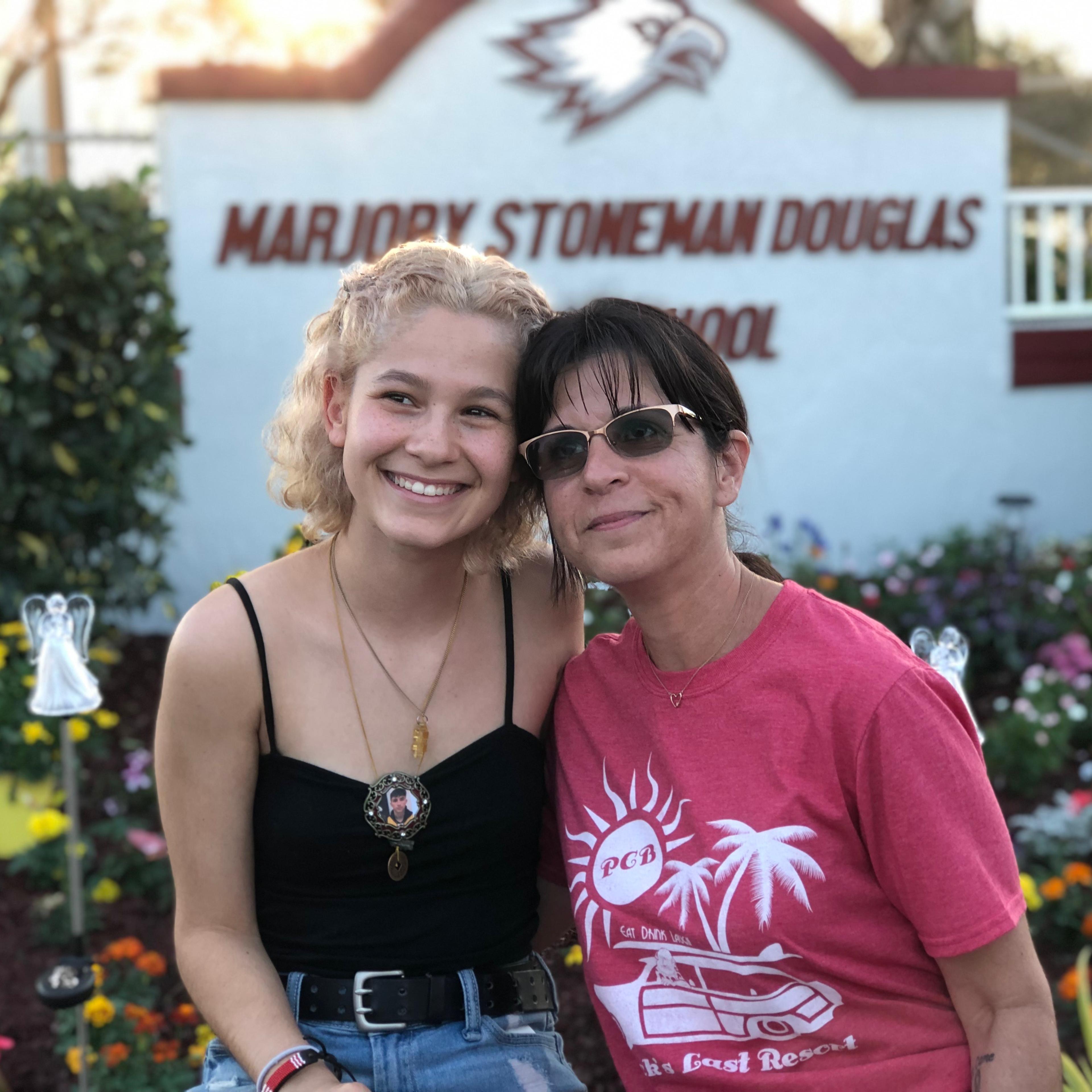 Stoneman Douglas senior Tori Gonzalez (left) and psychology teacher Ronit Reoven (right) sit in front of Project Grow Love, a garden memorial they built outside the school.