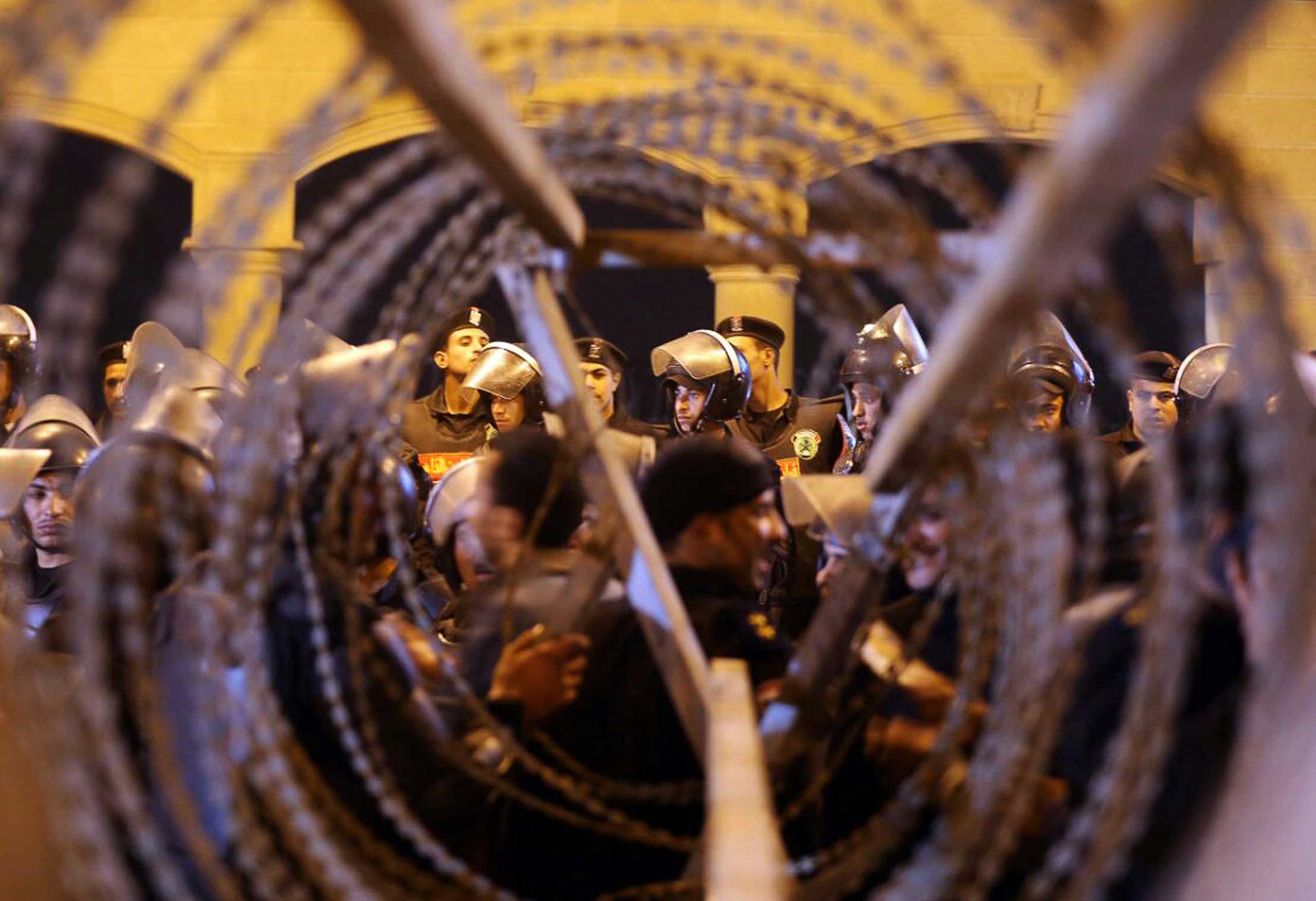 Policemen and soccer fans are seen through barbed wire as fans attempt to enter a stadium to watch a match, on the outskirts of Cairo, Feb. 8, 2015.