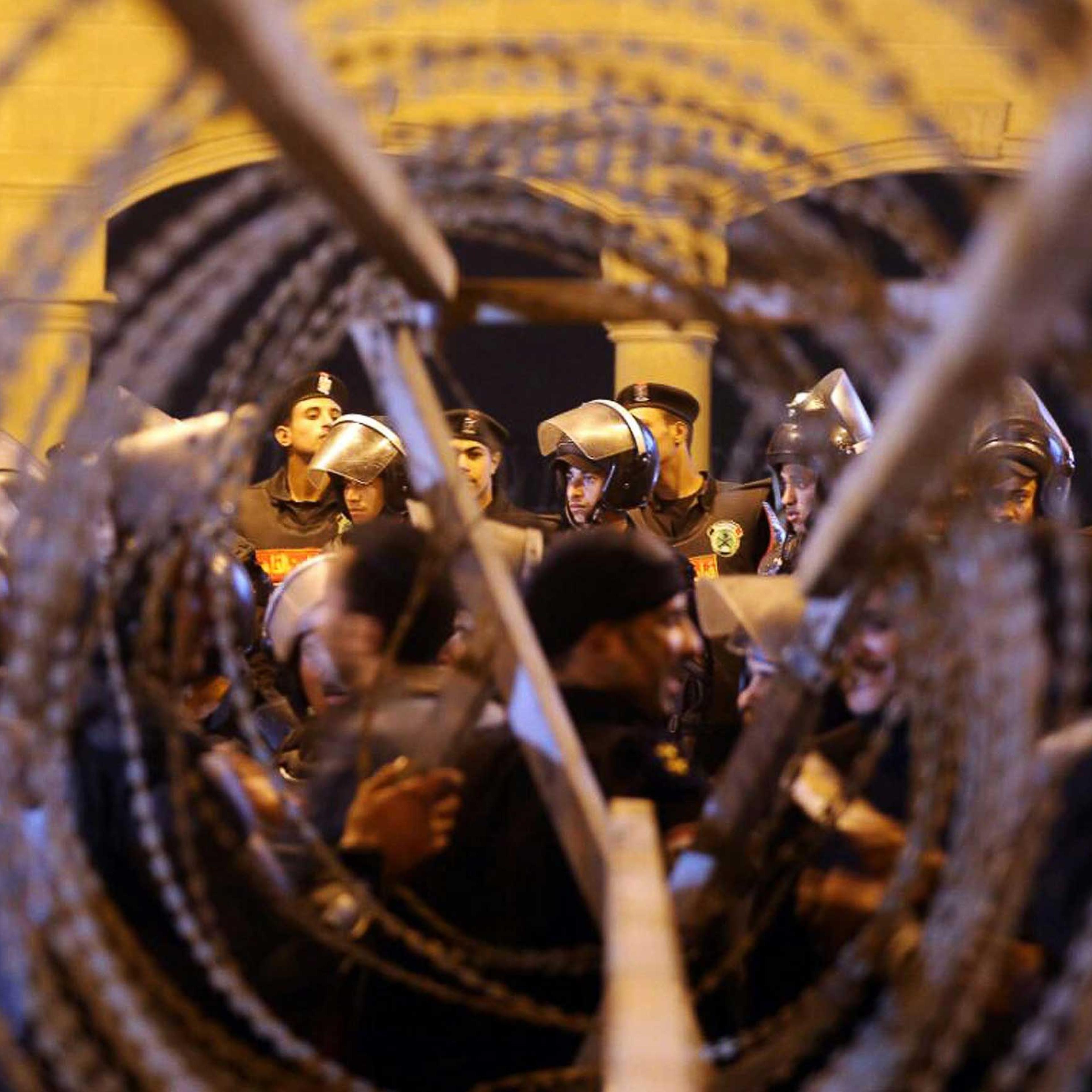 Policemen and soccer fans are seen through barbed wire as fans attempt to enter a stadium to watch a match, on the outskirts of Cairo, Feb. 8, 2015.