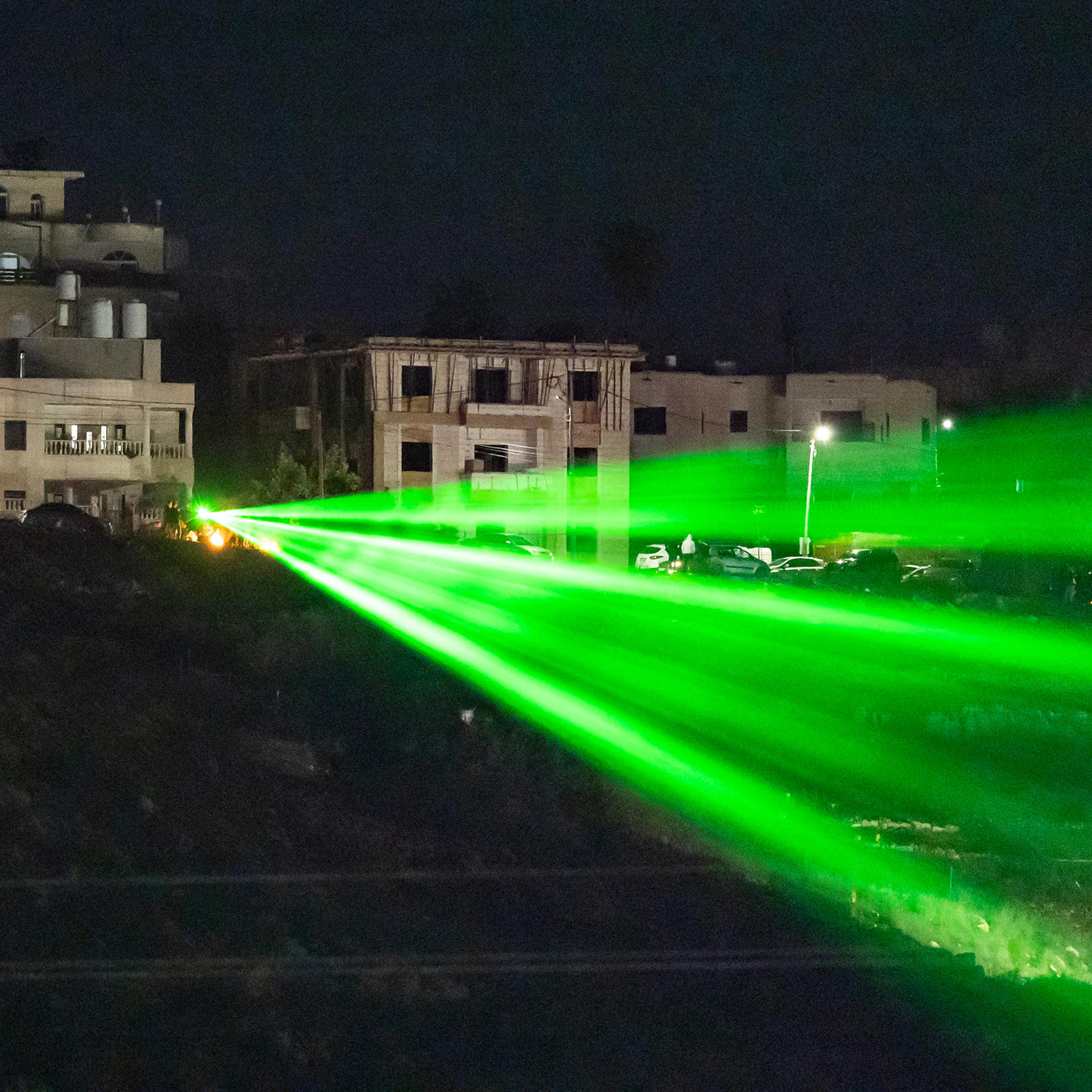 Palestinians direct a laser toward the Ofer military prison located between Ramallah and Beitunia in the occupied West Bank on Nov. 30, 2023, before the release of Palestinian prisoners in exchange for hostages held by Hamas in Gaza.