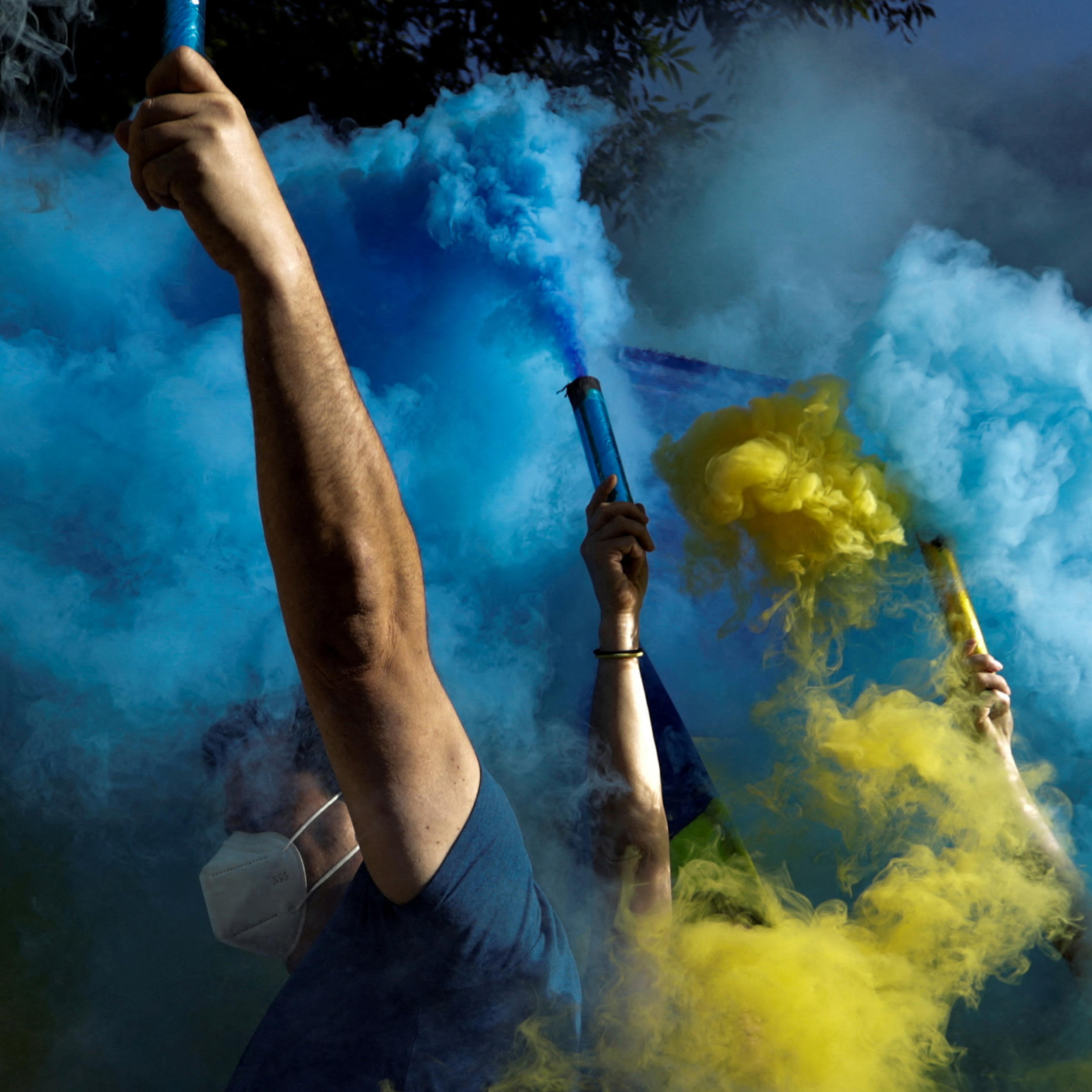 Protesters hold flares with the colors of the Ukrainian flag at an antiwar demonstration outside the Russian embassy in Mexico City on Feb. 28