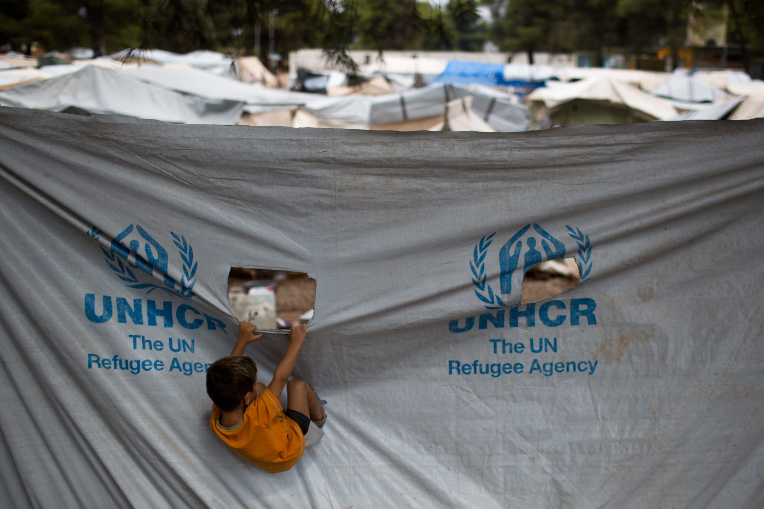 A child play in front of a UNHCR plastic sheet at Ritsona refugee camp, north of Athens, which hosts about 600 refugees and migrants on Thursday, Sept. 8, 2016. The refugee crisis is expected to be a central issue in discussions Friday at a meeting in At