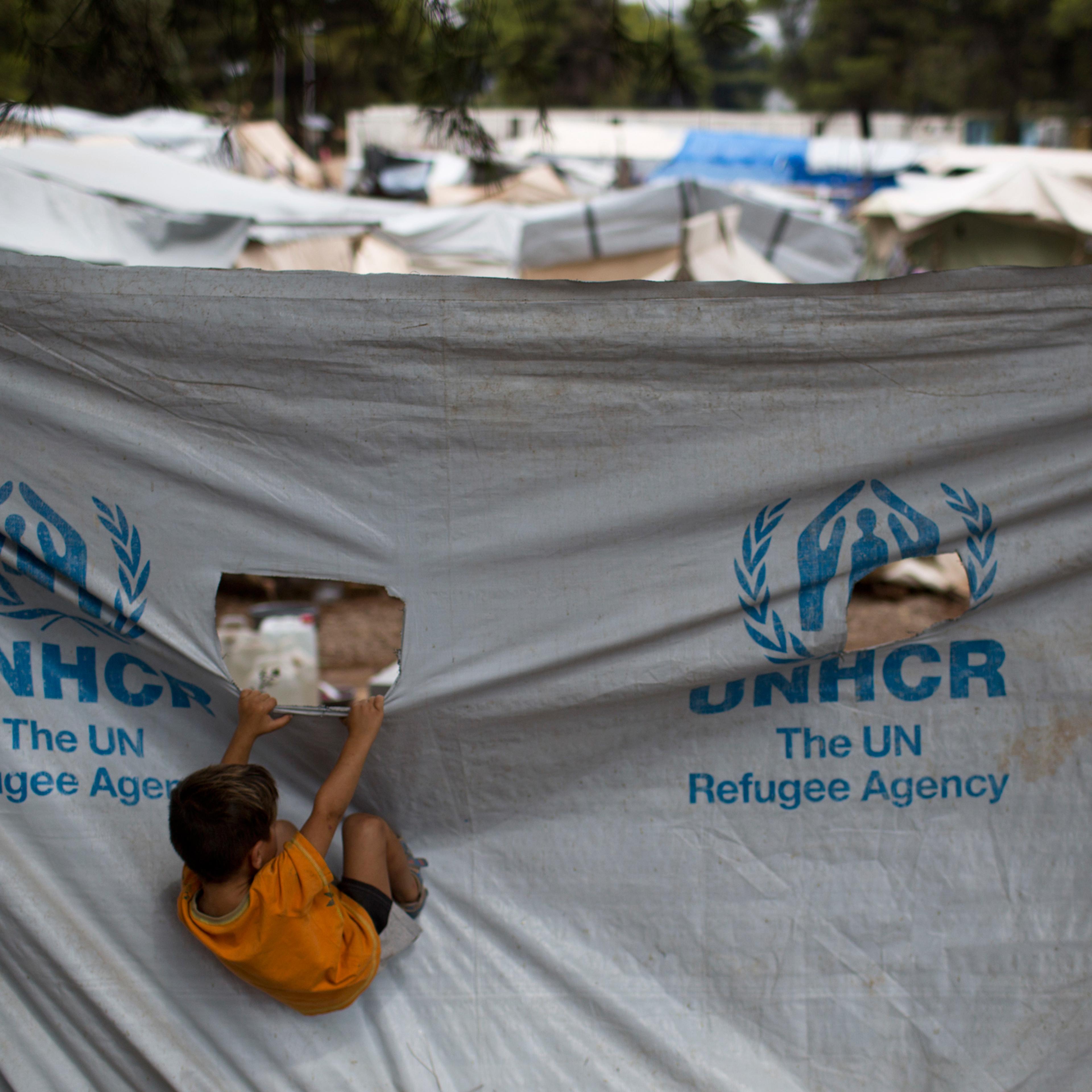 A child play in front of a UNHCR plastic sheet at Ritsona refugee camp, north of Athens, which hosts about 600 refugees and migrants on Thursday, Sept. 8, 2016. The refugee crisis is expected to be a central issue in discussions Friday at a meeting in At